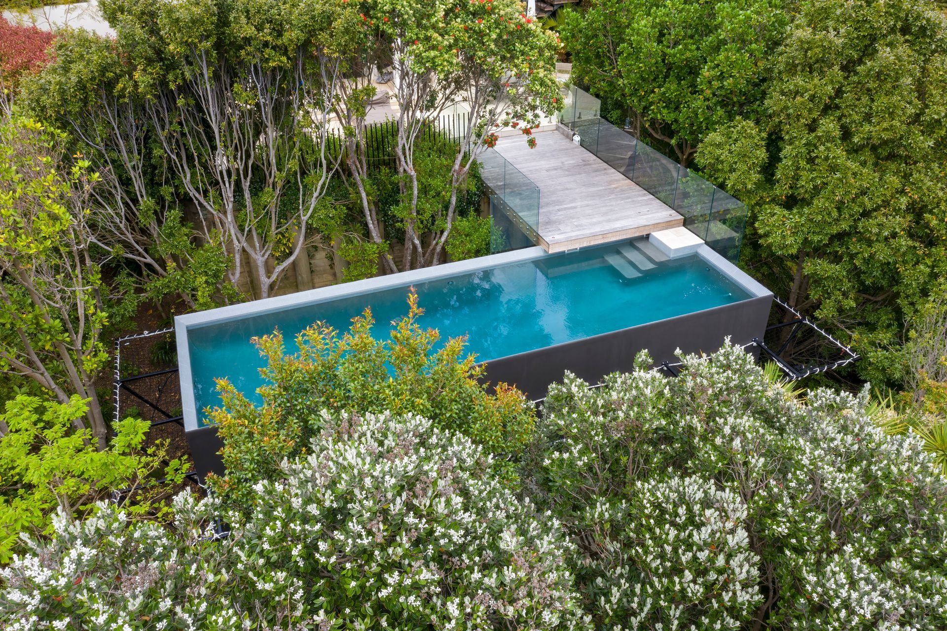 A custom built 10m x 3m pool with a volume of 45,000L is nestled among the tree tops in suburbia as part of a greater landscaping project to make good use of a redundant space.