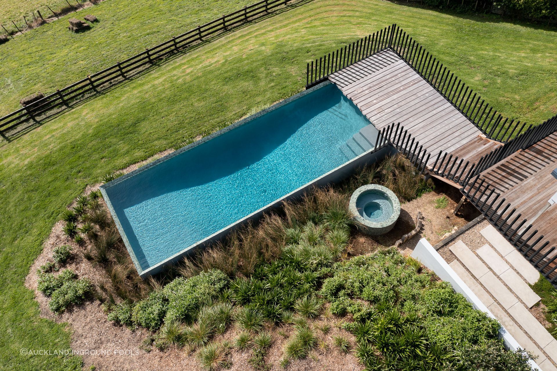 Using the existing lay of the land, this above-ground rectangular pool and circular garden spa are embraced by flourishing native planting.