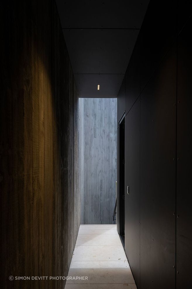 The darker, more enclosed passages give the home a sense of sequence, balancing openness to the view with moments of privacy and retreat.