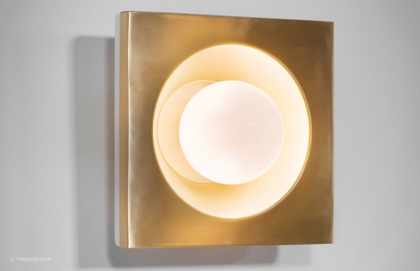 The Kins Wall Light and its warm Brass lacquered metal finish.