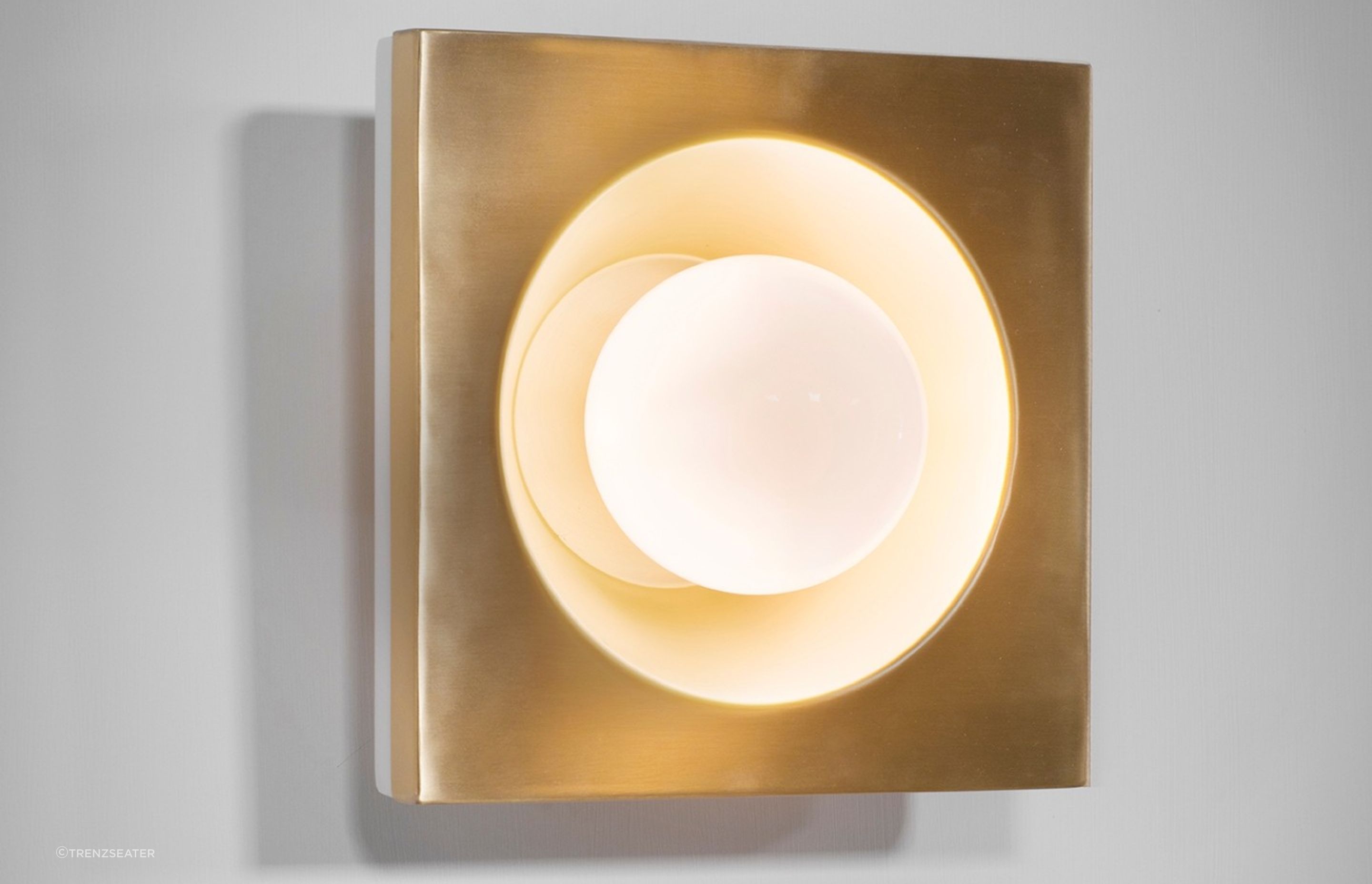 The Kins Wall Light and its warm Brass lacquered metal finish.