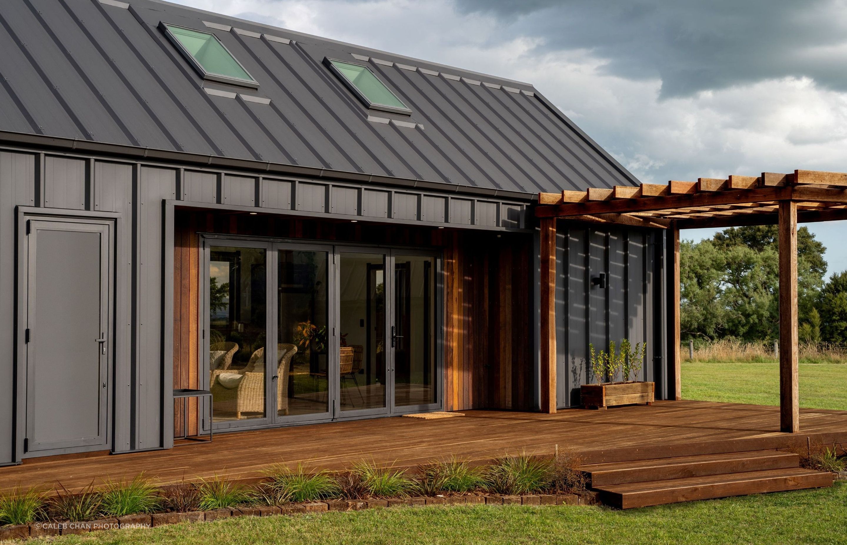 Kāhu Cottage features a beautiful deck with a pergola made of reclaimed hardwood. | Photography: Caleb Chan Photography