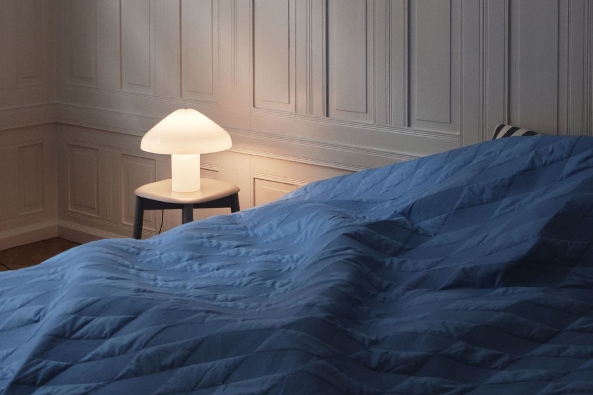 A bedside table can set the stage for a designer lamp like the Pao Glass Table Lamp by HAY.