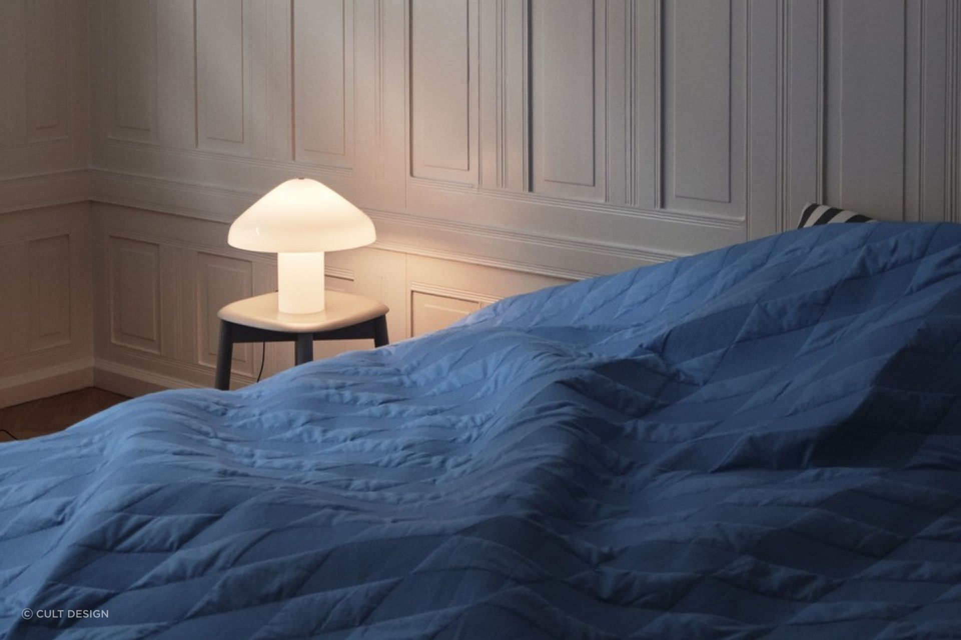 A bedside table can set the stage for a designer lamp like the Pao Glass Table Lamp by HAY.