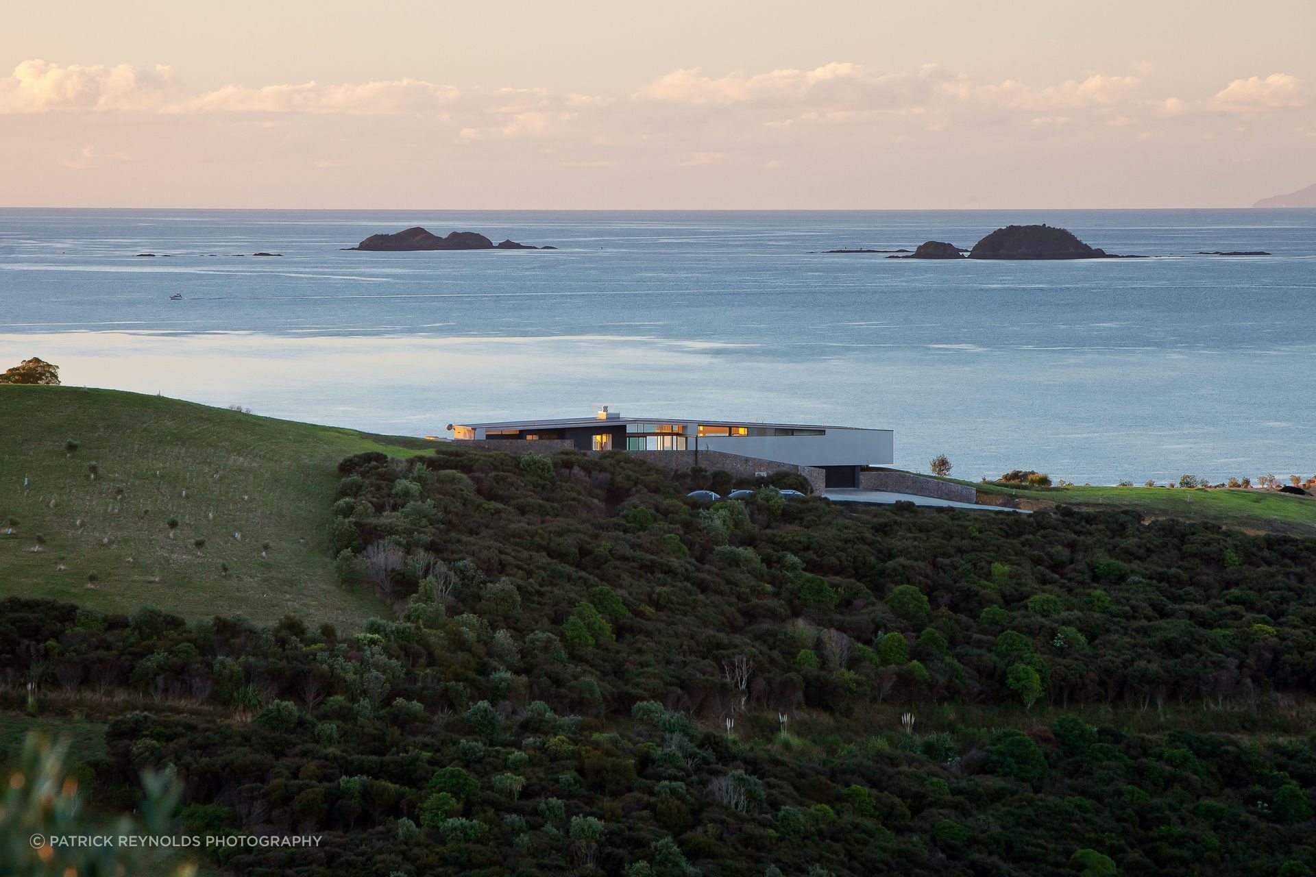 Korora House by Daniel Marshall Architects sits low against the coastline, with Waiheke Stone elements grounding the contemporary form in the island landscape | Photography by Patrick Reynolds