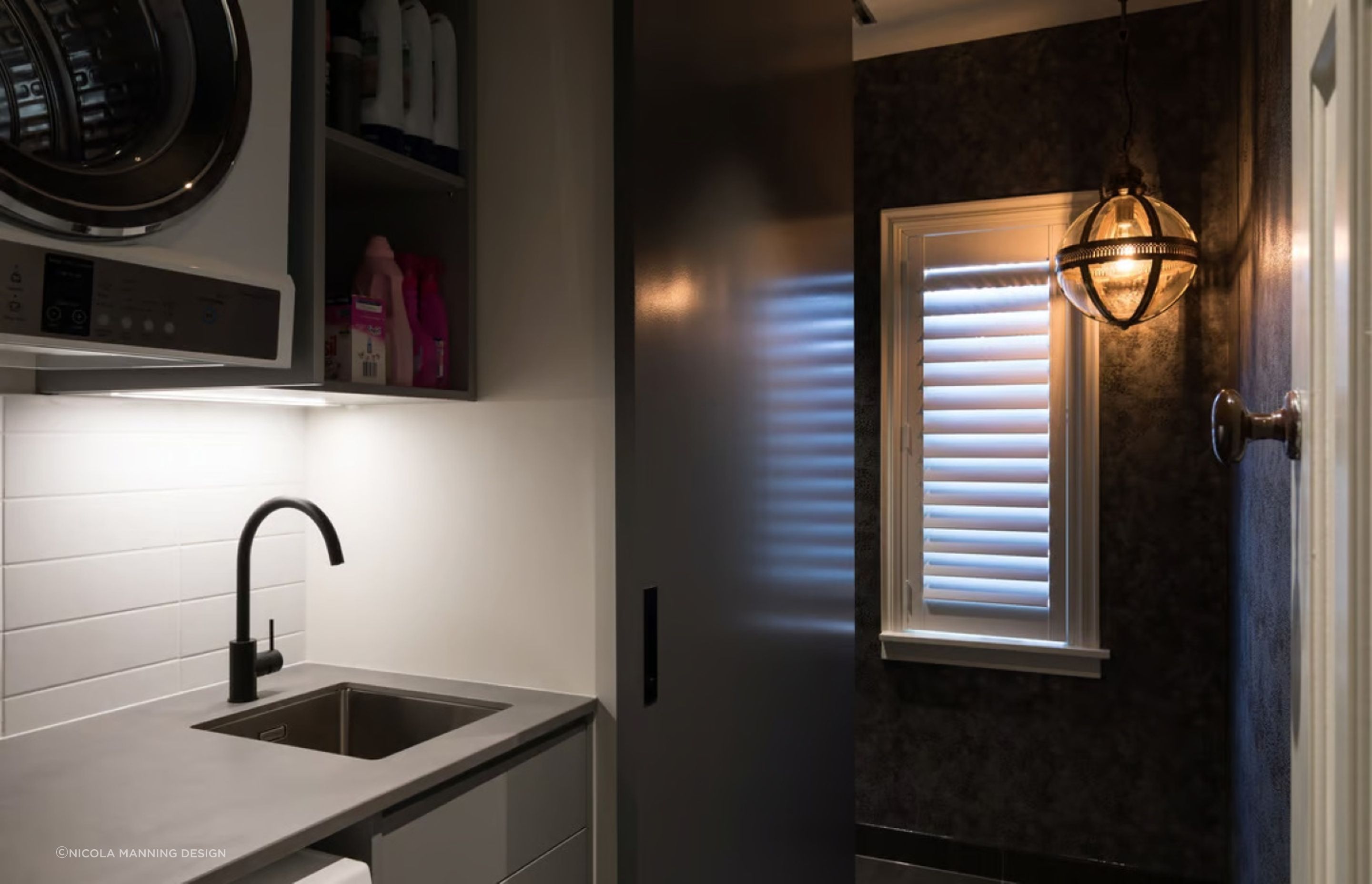 This designer pendant light sets a bold and unique mood in this stylish laundry room designed by Nicola Manning Design.