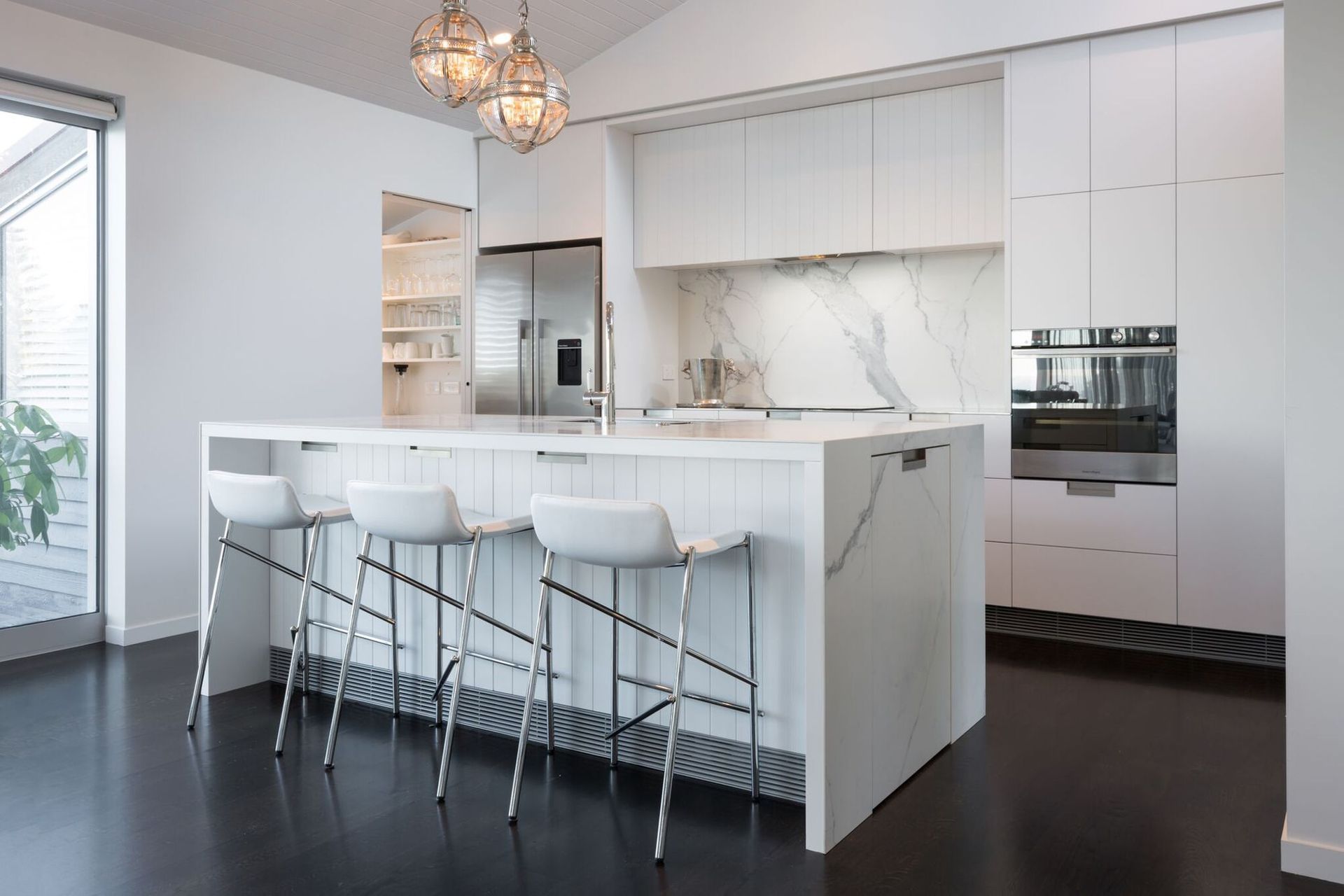 Recessed kitchen cabinet handles seamlessly allows the immaculate design of this Mairangi Bay home to shine.