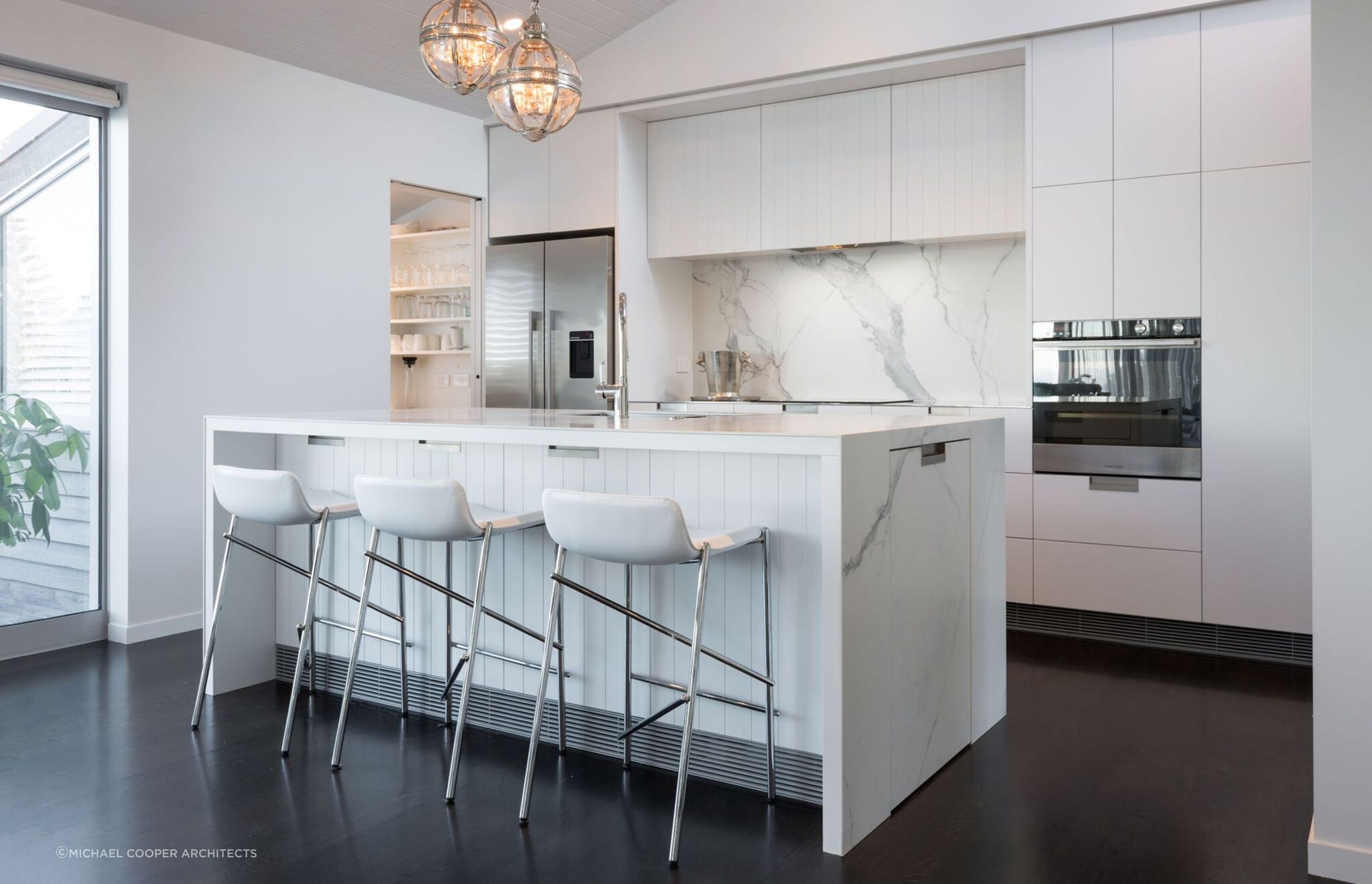Recessed kitchen cabinet handles seamlessly allows the immaculate design of this Mairangi Bay home to shine.