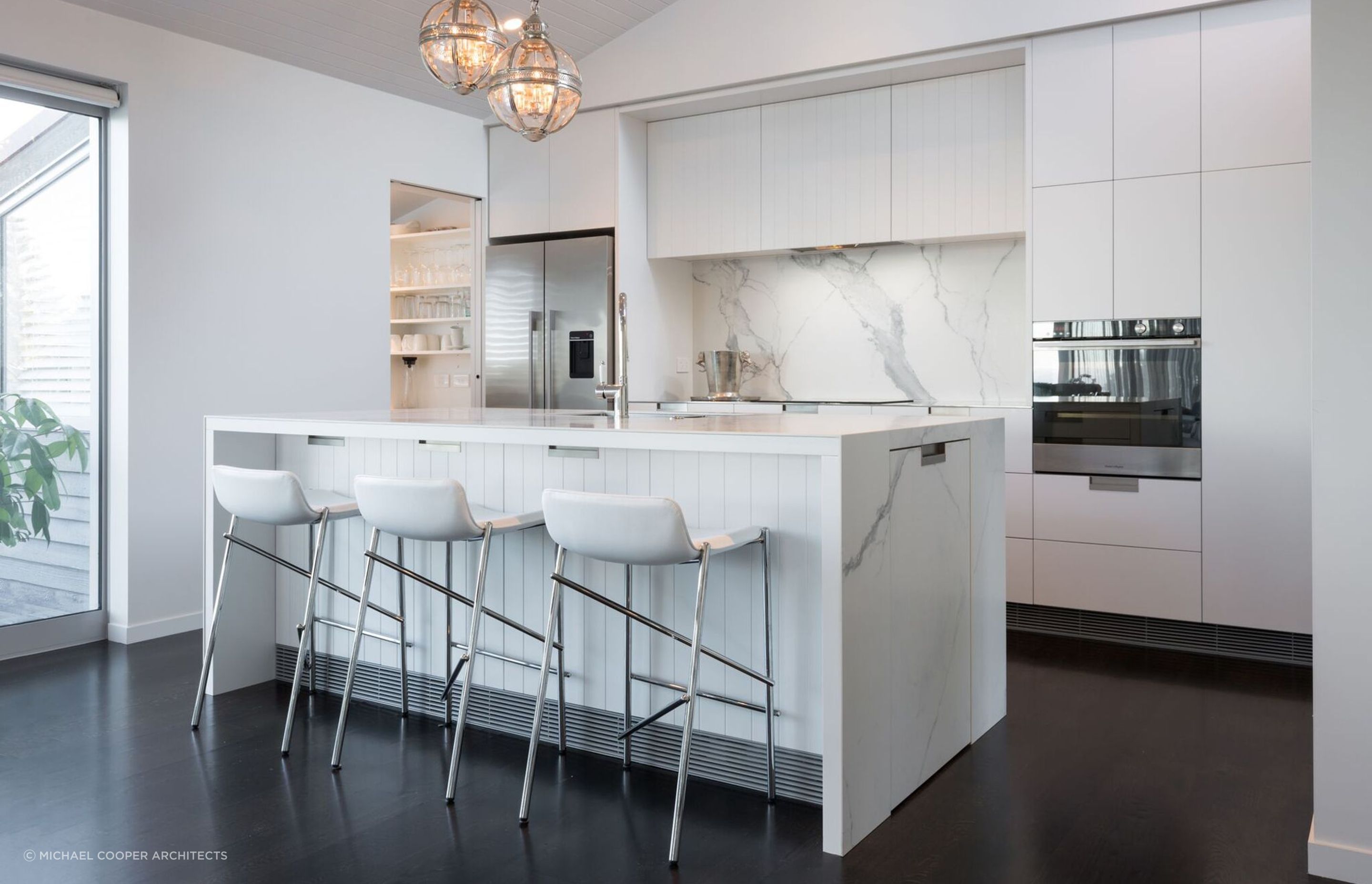 Recessed kitchen cabinet handles seamlessly allows the immaculate design of this Mairangi Bay home to shine.