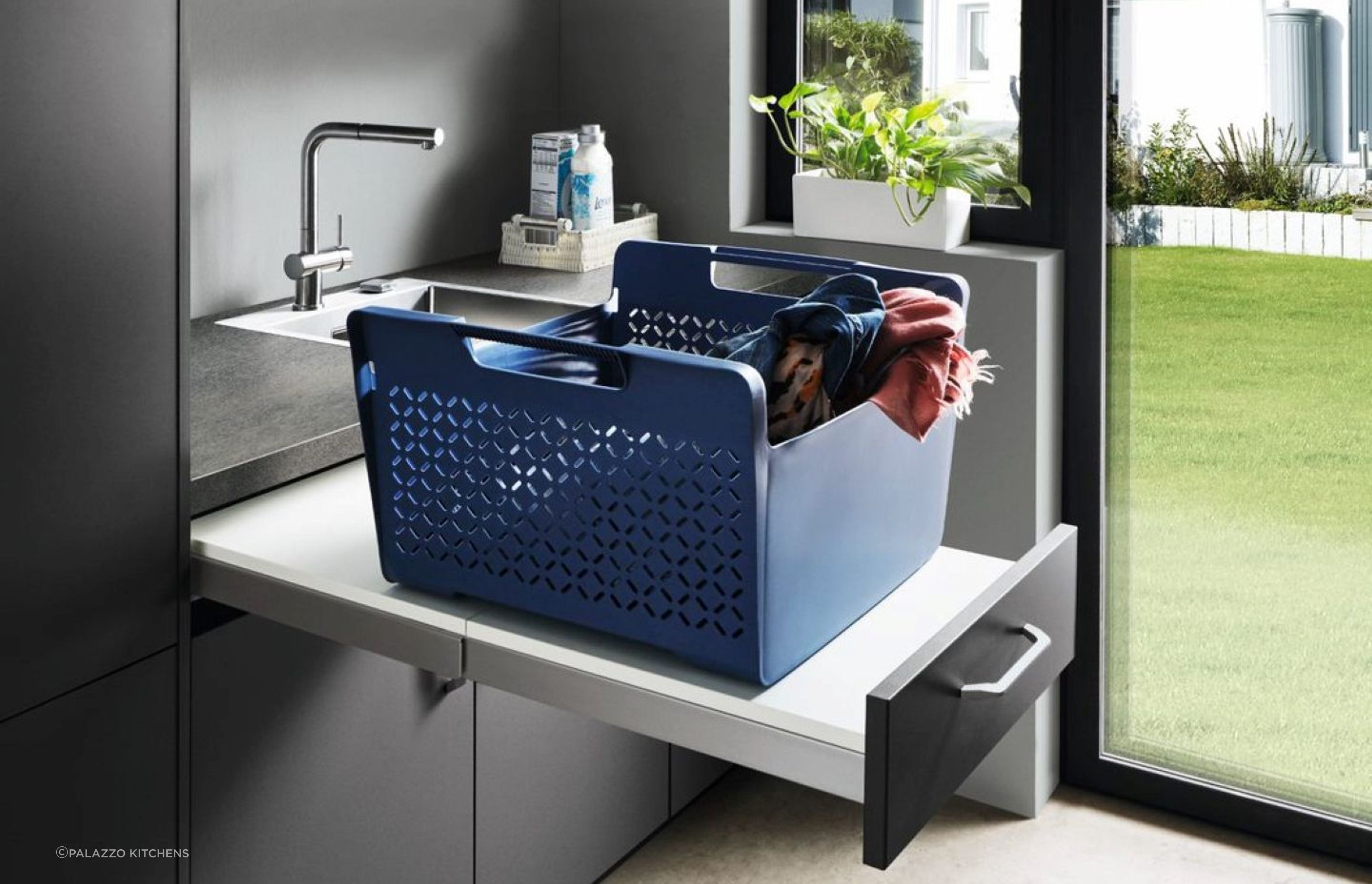 A pull-out surface can make your daily laundry chores so much easier, demonstrated with aplomb here using Touch Laundry Cabinetry by Nobilia.