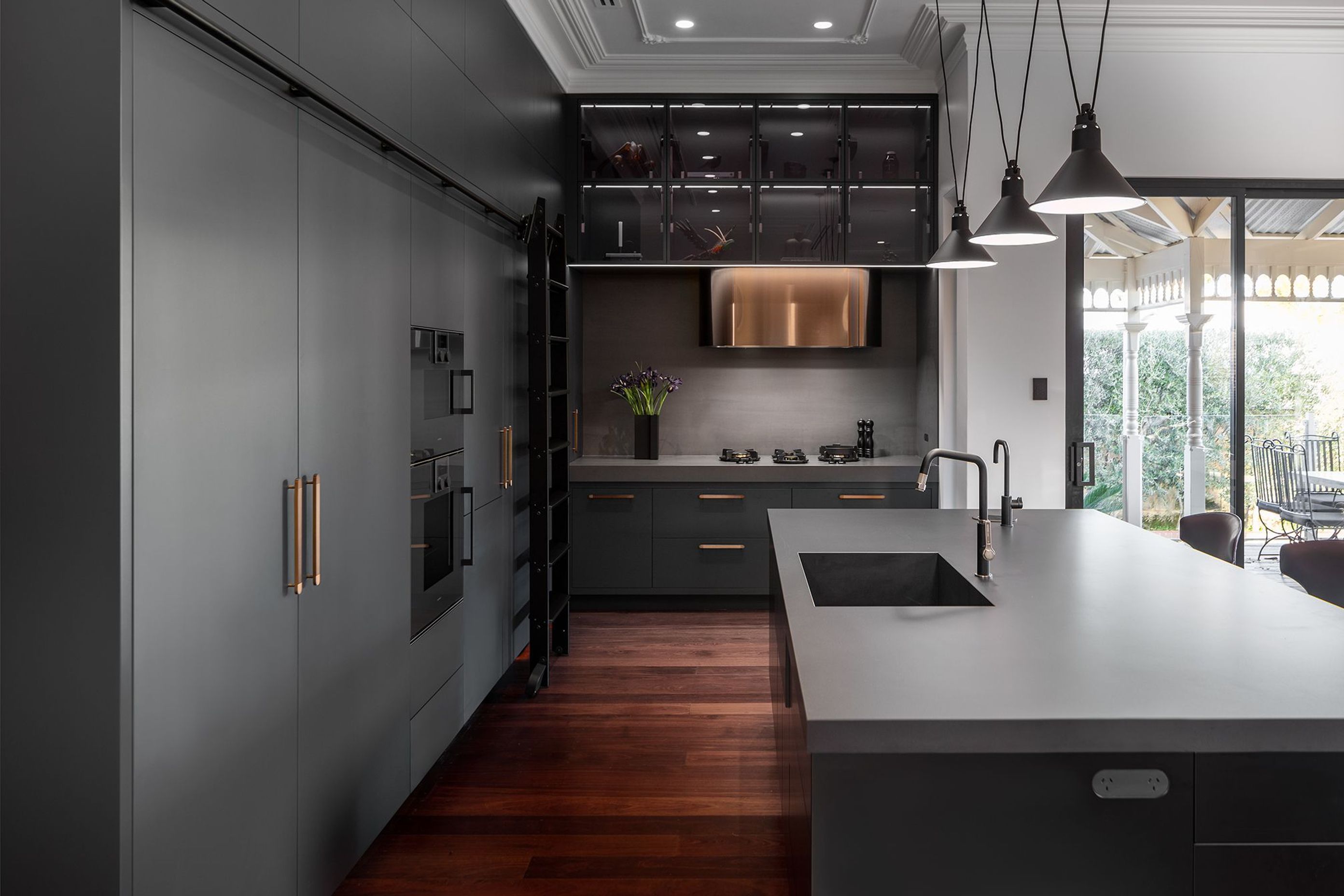 The rolling library ladder is a unique touch in the bold kitchen of the Park Project. | Photography: Silvertone Photography