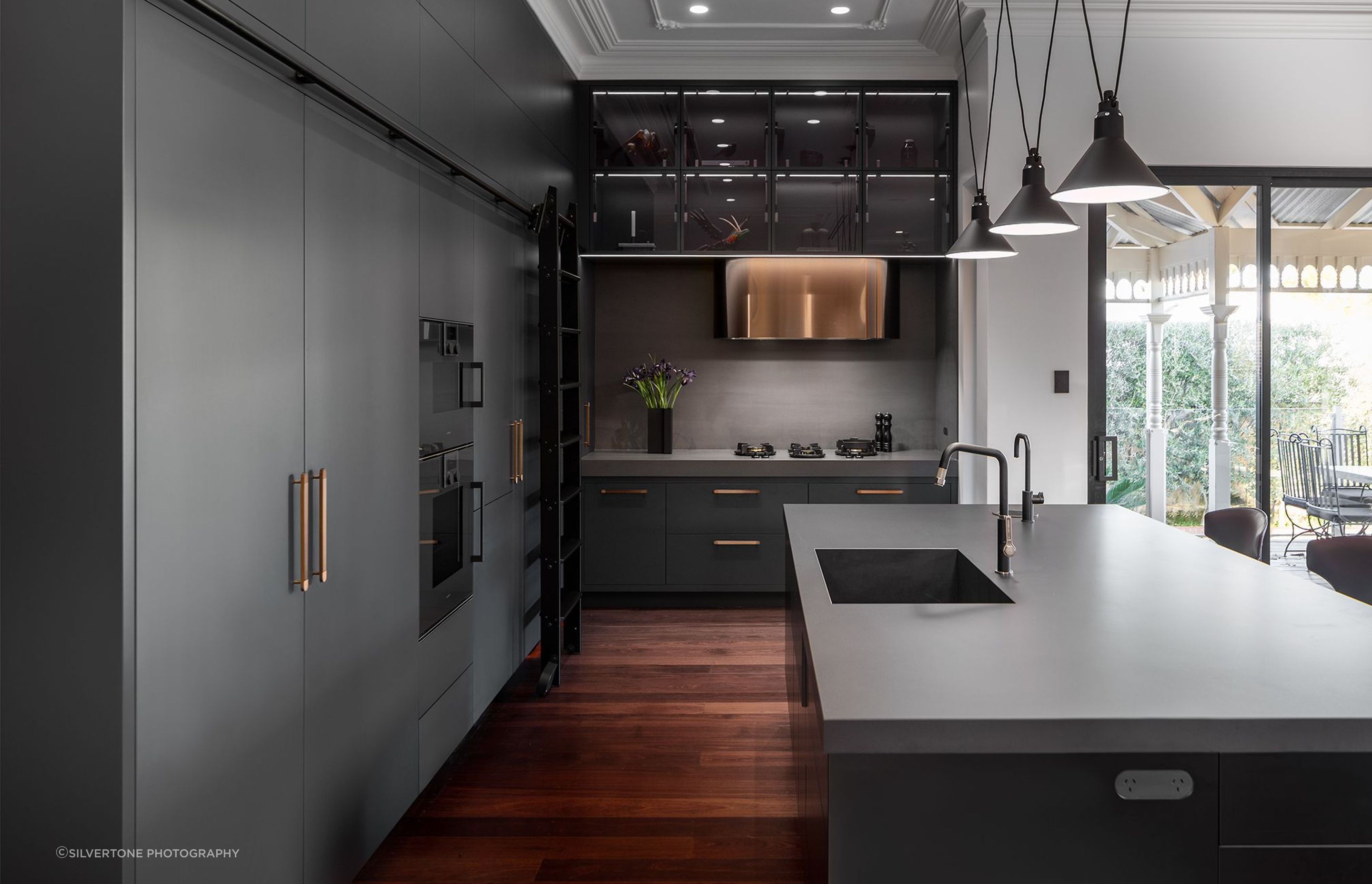 The rolling library ladder is a unique touch in the bold kitchen of the Park Project. | Photography: Silvertone Photography