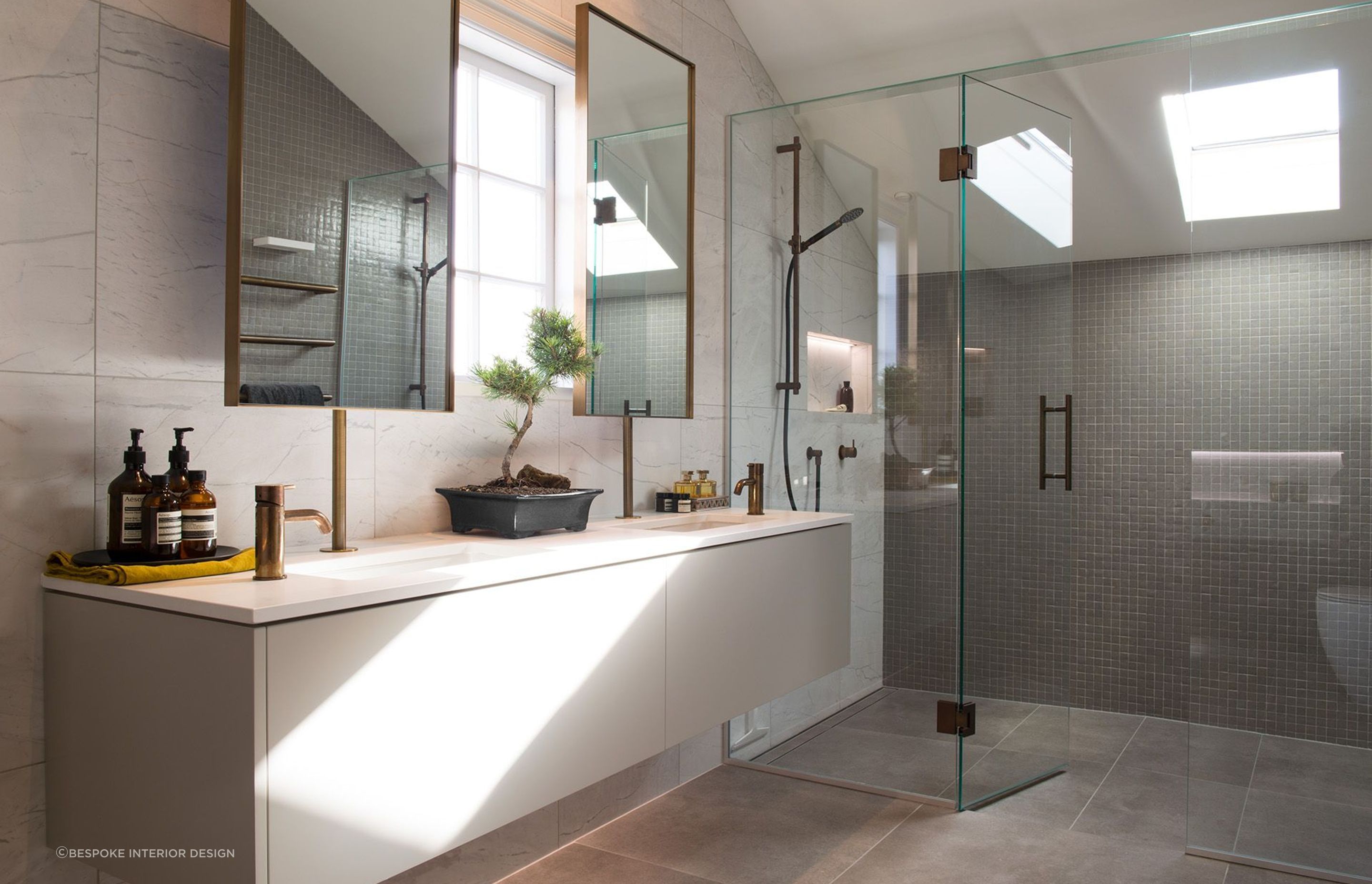 The beautiful bathroom renovation of Rangitoto House featuring vanity-mounted mirrors.