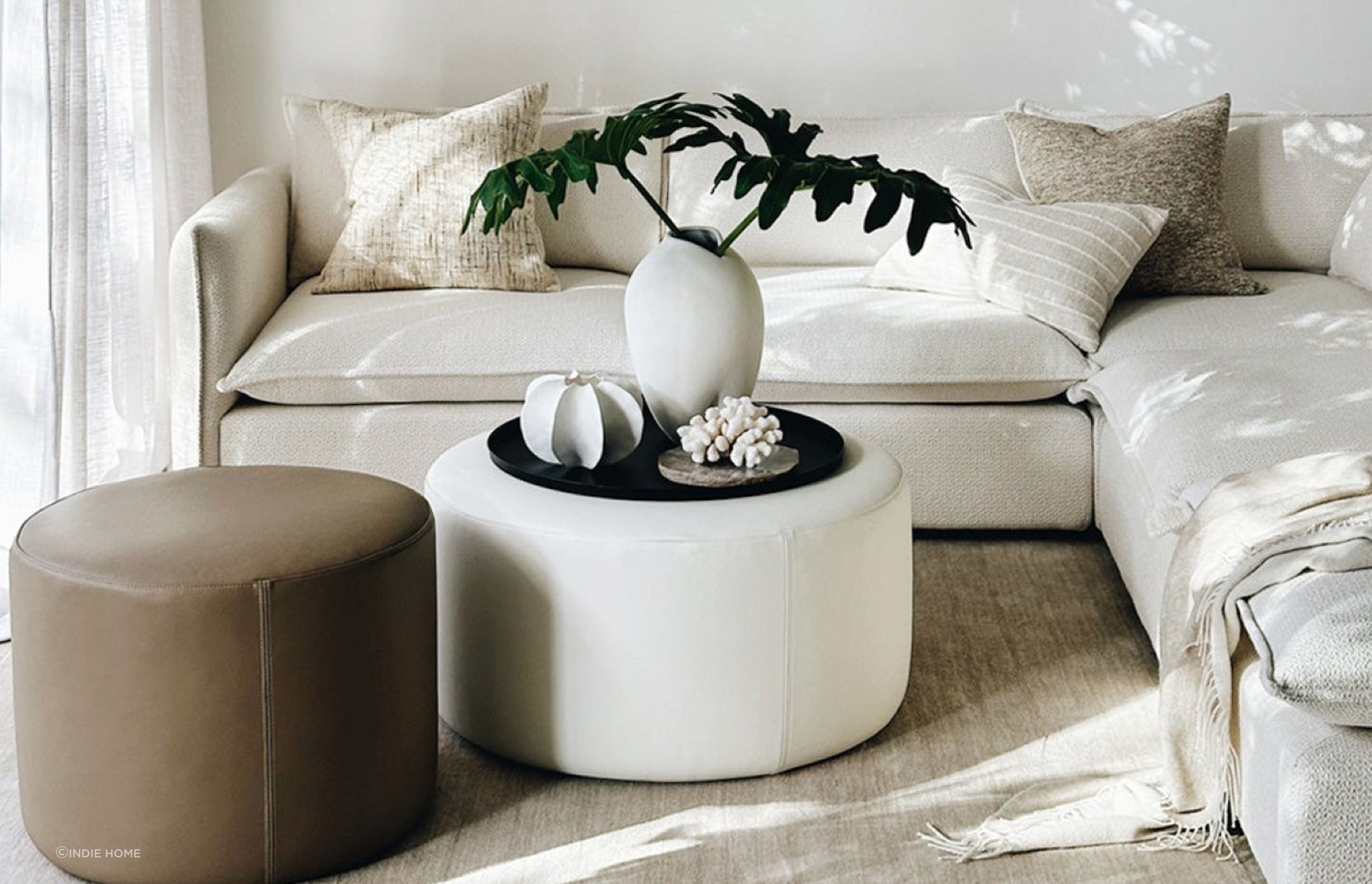 The 'Rio' Ottoman in Cream Leather from Indie Home sets a great stage for decorative pieces.