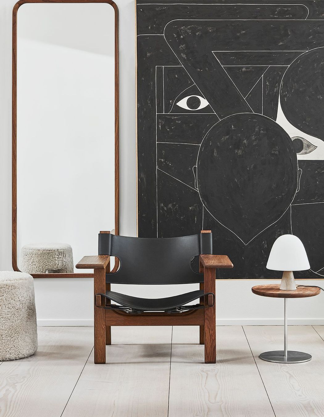 The sleek Silhouette Mirror Rectangle by Fredericia positioned behind an armchair and stool.