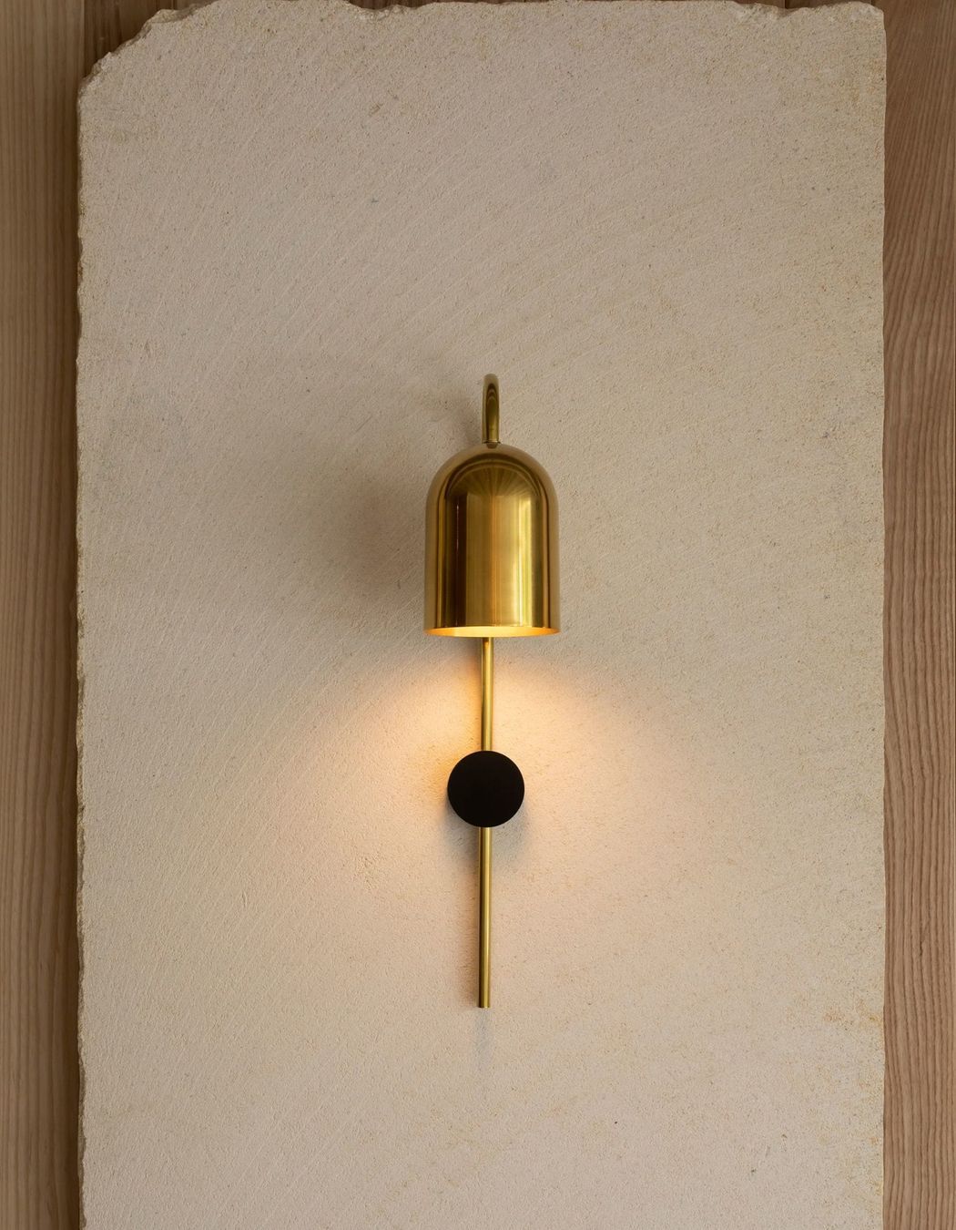 A sleek golden sconce illuminates the natural beauty of the limestone.