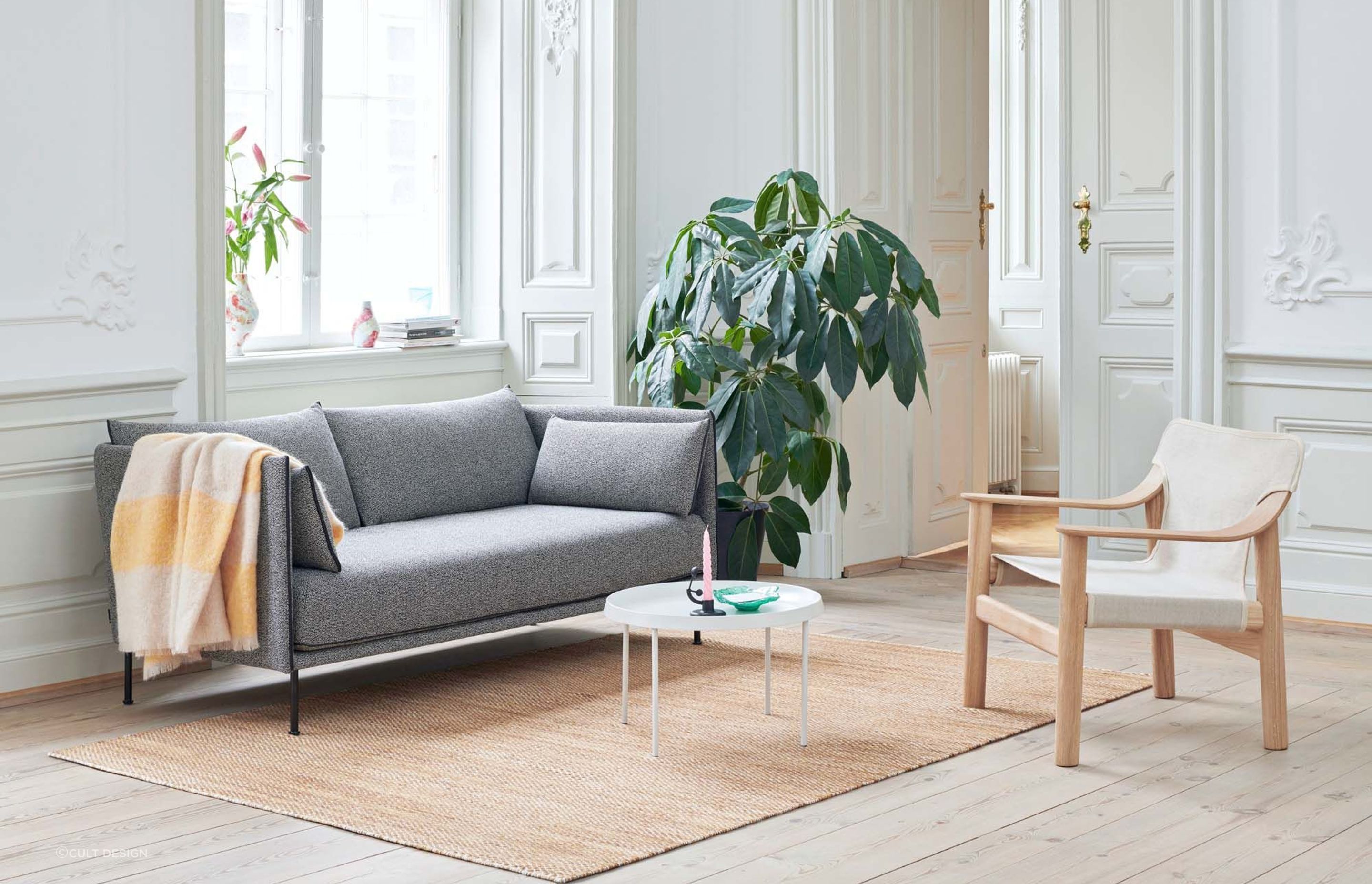 The inclusion of plants can bring freshness and vitality to a living space, seen here alongside the chic Silhouette Sofa by Hay.