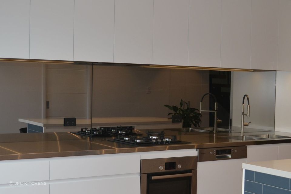 A modern take on chef's kitchen by JPC Kitchens, featuring a sleek stainless steel benchtop.