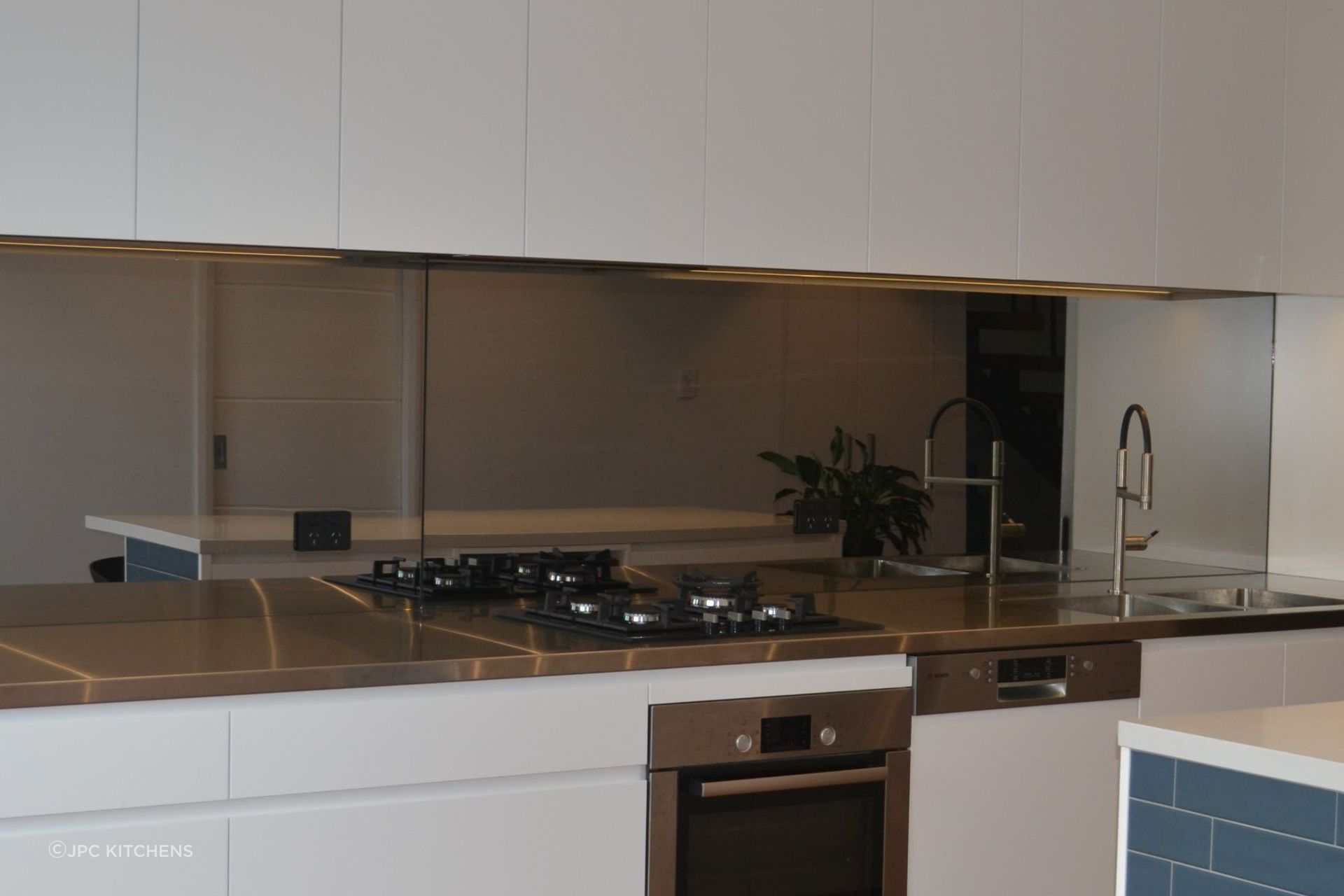 A modern take on chef's kitchen by JPC Kitchens, featuring a sleek stainless steel benchtop.