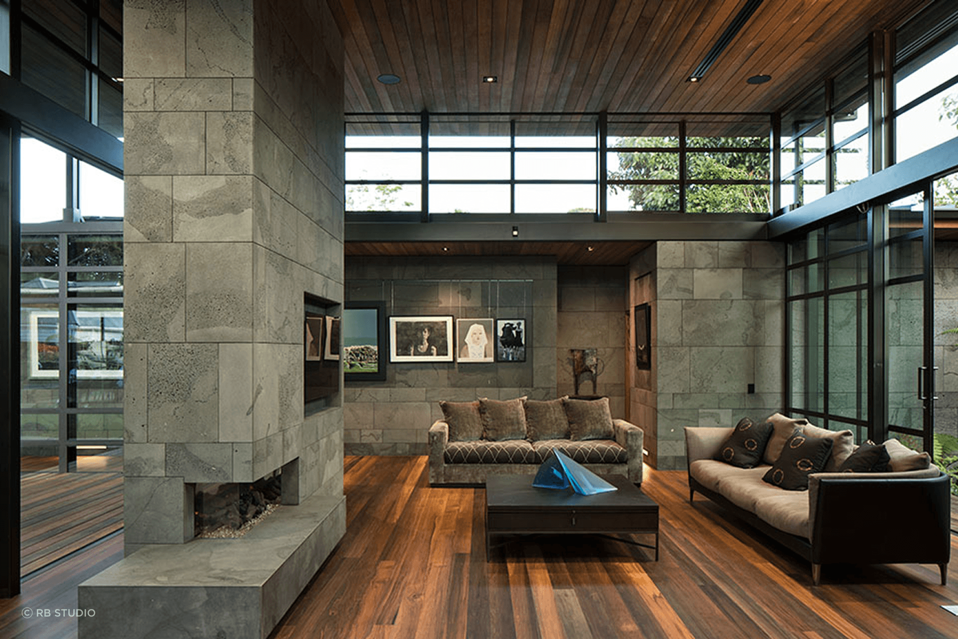 Inside Volcano House by RB Studio, Timaru Bluestone walls and chimney are paired with rich riverwood flooring to create a calm, gallery-like living space.