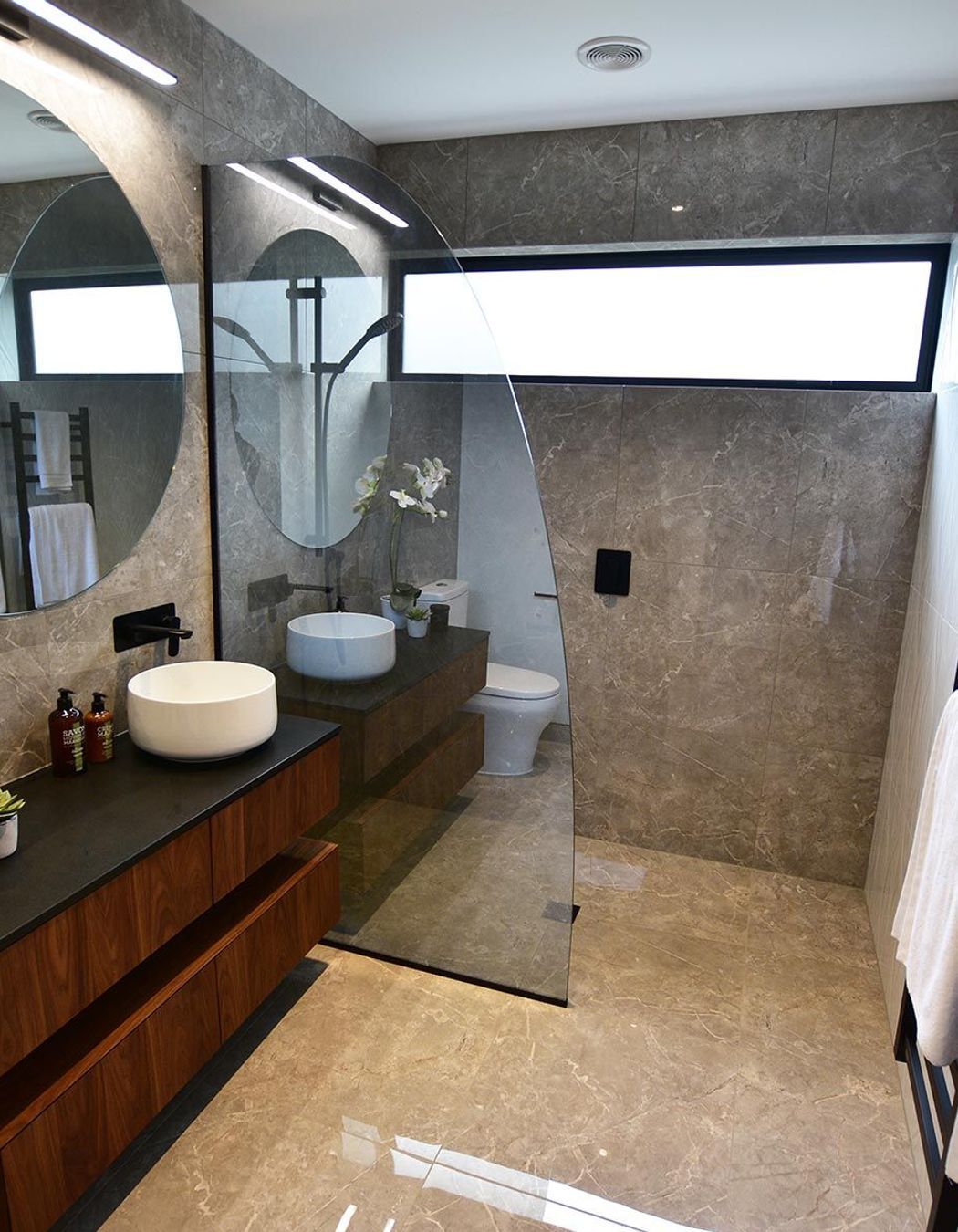 Tinted and curved, this glass shower screen adds a touch of personality to the bathroom.
