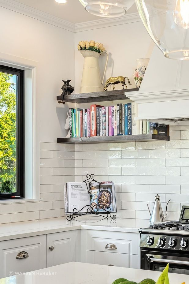 Wall shelving increases kitchen storage while providing the perfect space for an uninterrupted display of the homeowner's personal treasures and curated collection of recipe books.