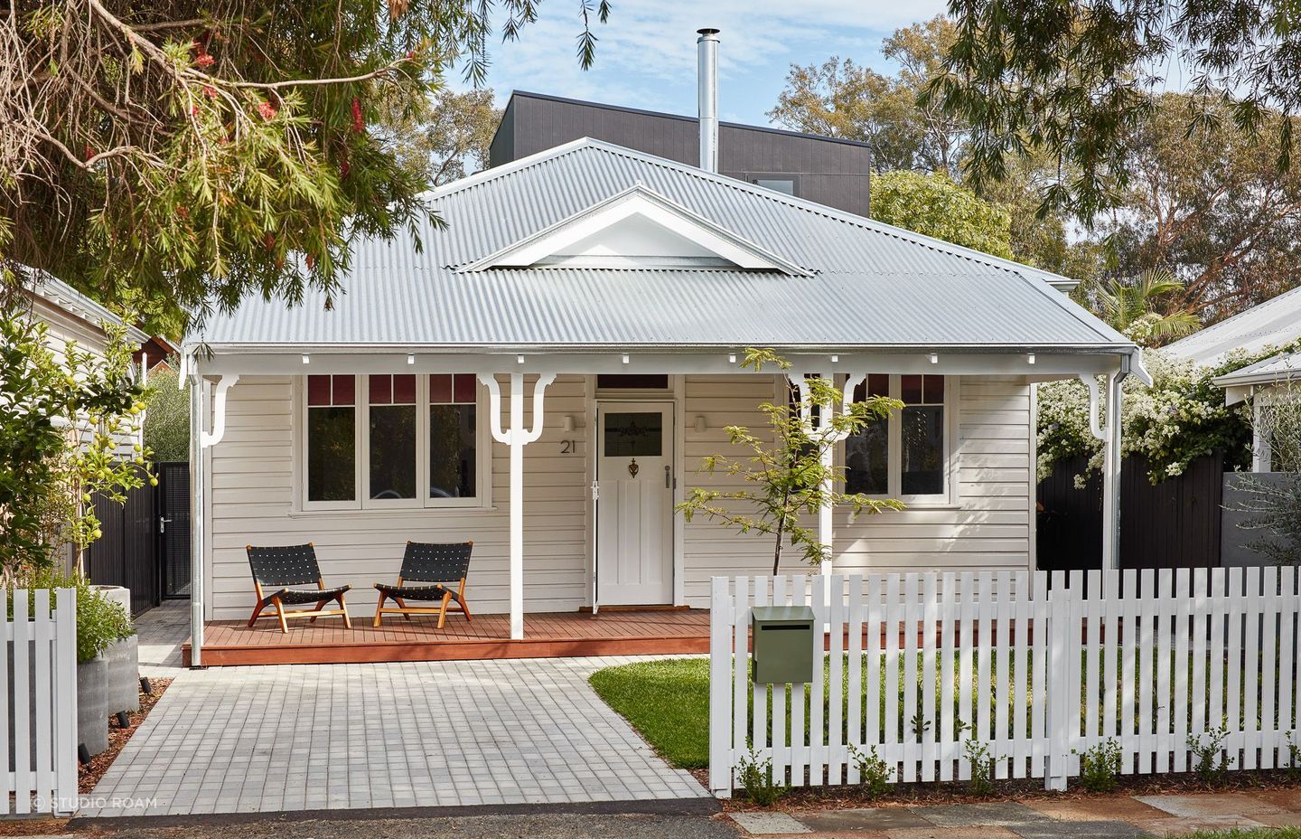 The white front door of this home, flanked by matching pillars, presents a cohesive and elegant entryway, reflecting a thoughtful design that values simplicity and symmetry. Featured project: Shadow House by Studio Roam