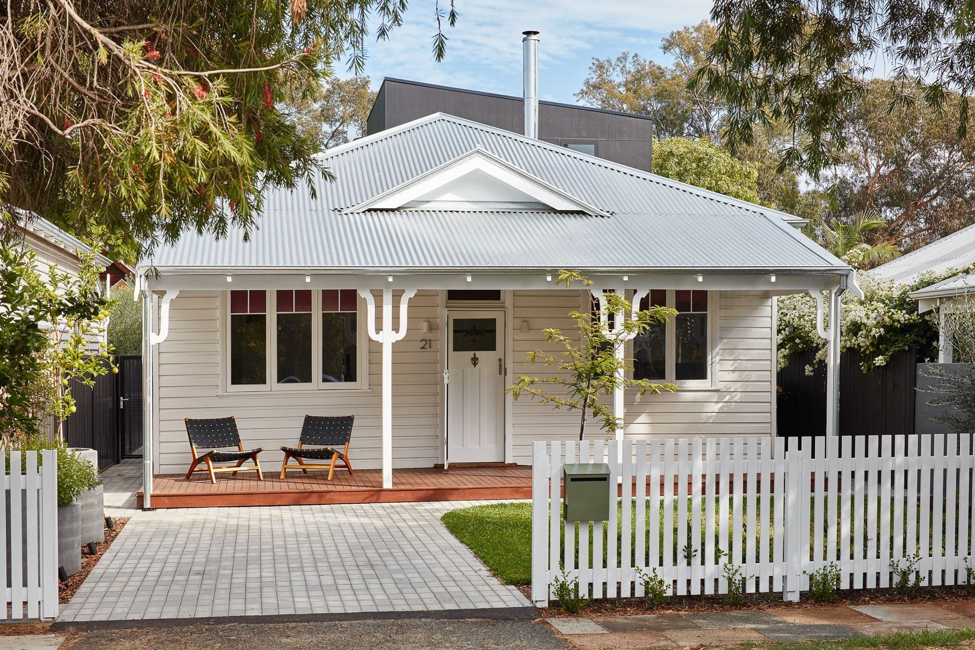 The white front door of this home, flanked by matching pillars, presents a cohesive and elegant entryway, reflecting a thoughtful design that values simplicity and symmetry. Featured project: Shadow House by Studio Roam