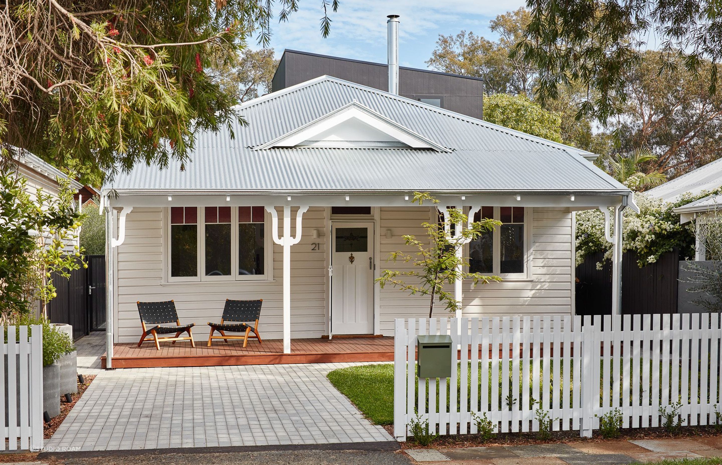 The white front door of this home, flanked by matching pillars, presents a cohesive and elegant entryway, reflecting a thoughtful design that values simplicity and symmetry. Featured project: Shadow House by Studio Roam