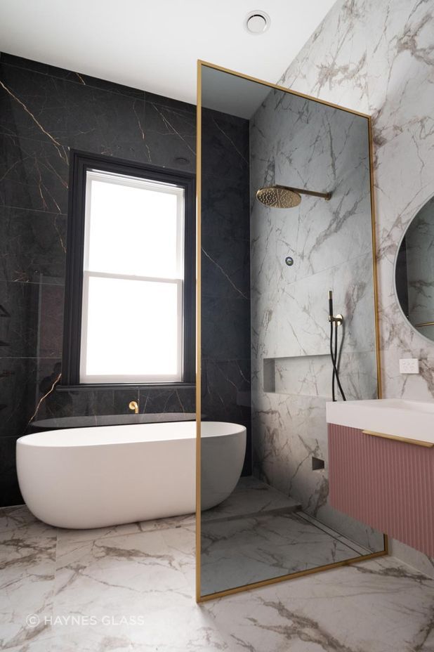 With a soft tint and gold frame, this glass shower screen is sleek and elegant.
