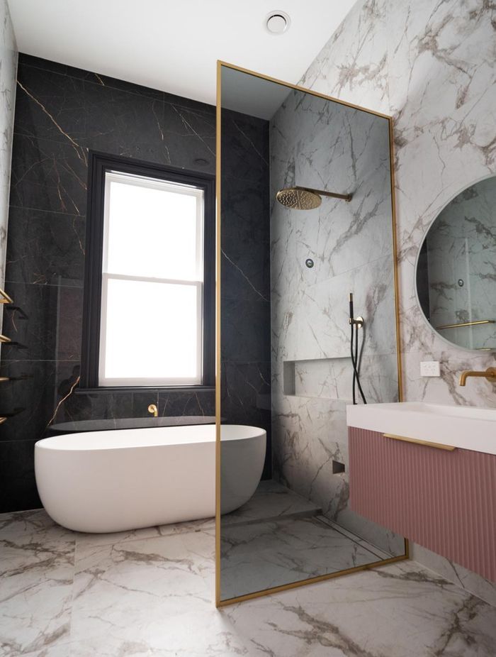 With a soft tint and gold frame, this glass shower screen is sleek and elegant.