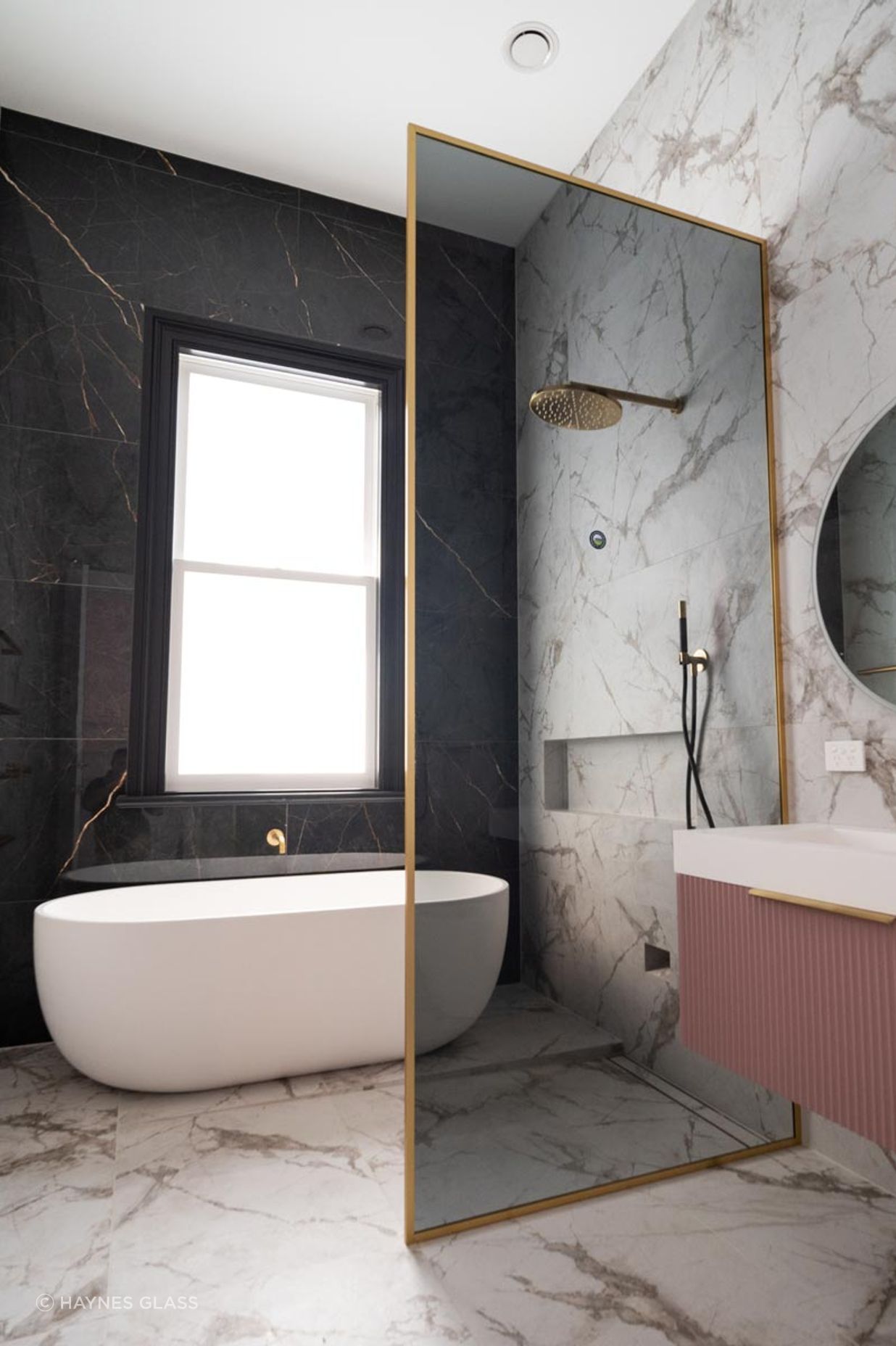 With a soft tint and gold frame, this glass shower screen is sleek and elegant.