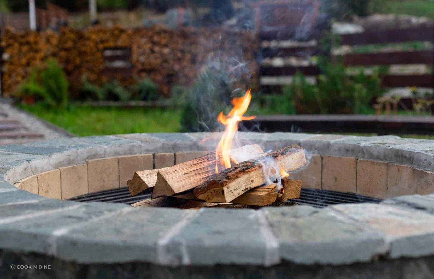 zone-relax-with-burning-fire-pit-couch-against-lawn-wood-fence-rest-relaxation-concept-2048x1395.jpg