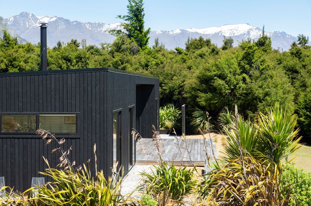 Snow-covered mountains backdrop the char-black home.