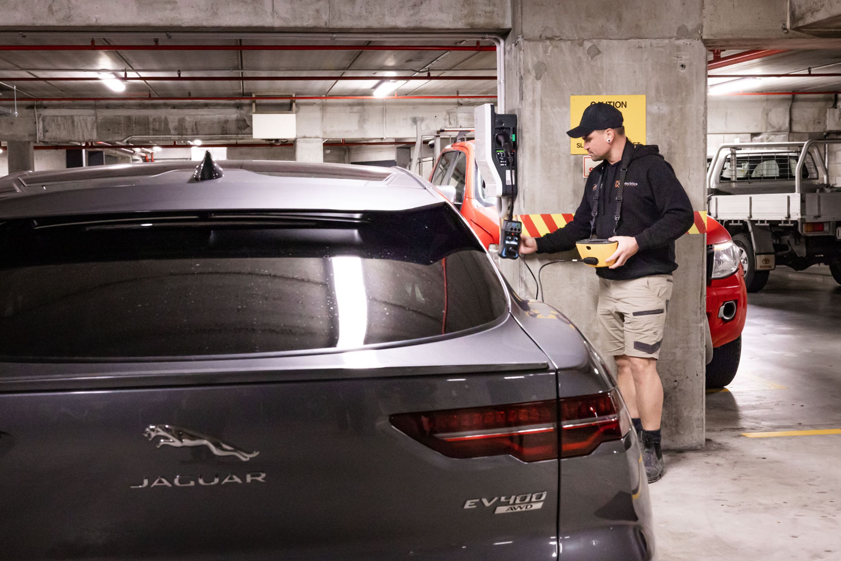 A K C Electrics team member tests and commissions an EV charger using dedicated test equipment.