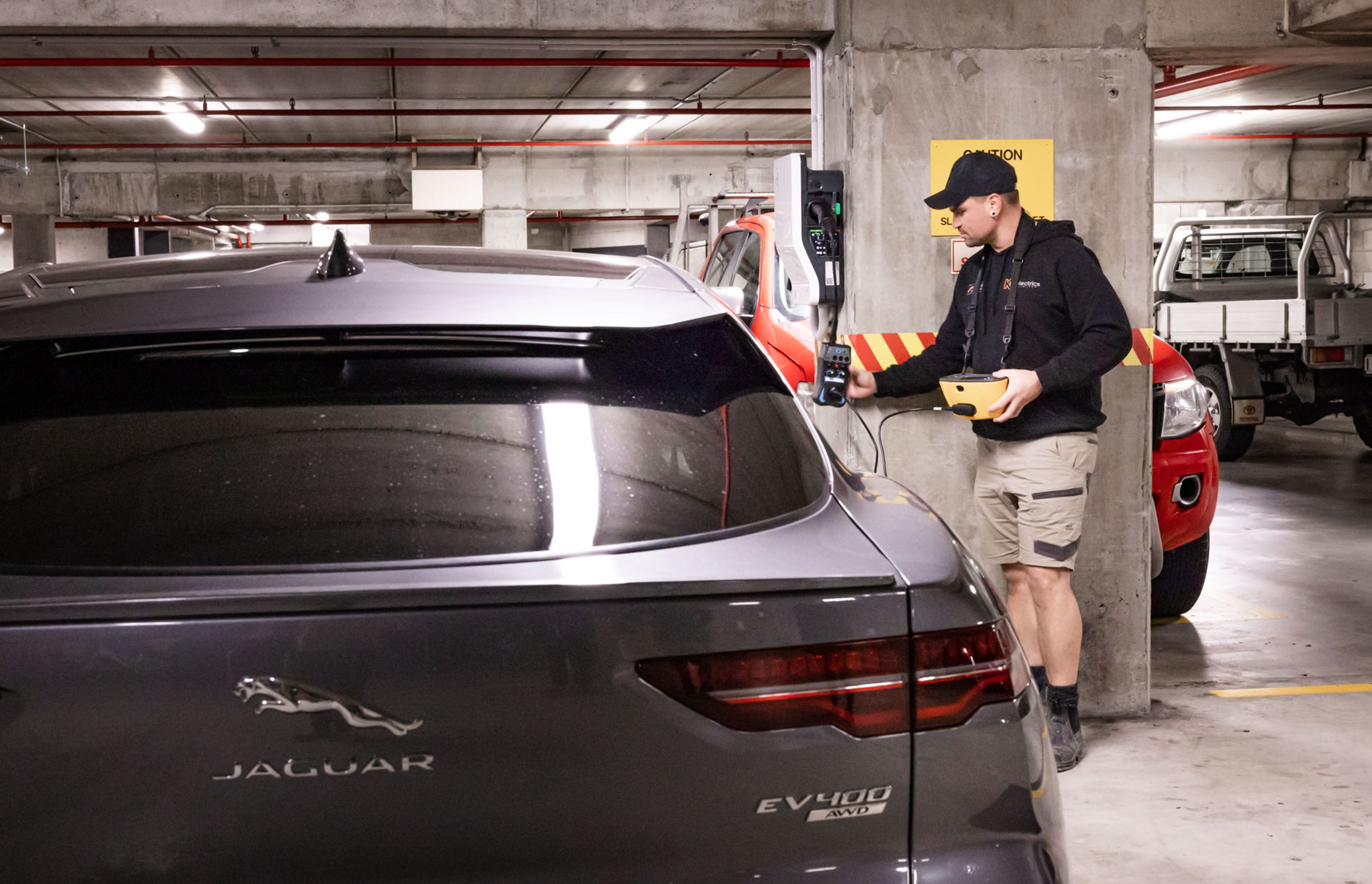 A K C Electrics team member tests and commissions an EV charger using dedicated test equipment.