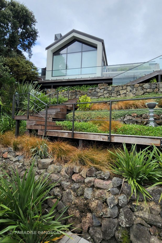The steep site called for hardwood stairs to a deck surrounded by clusters of native shrubs.