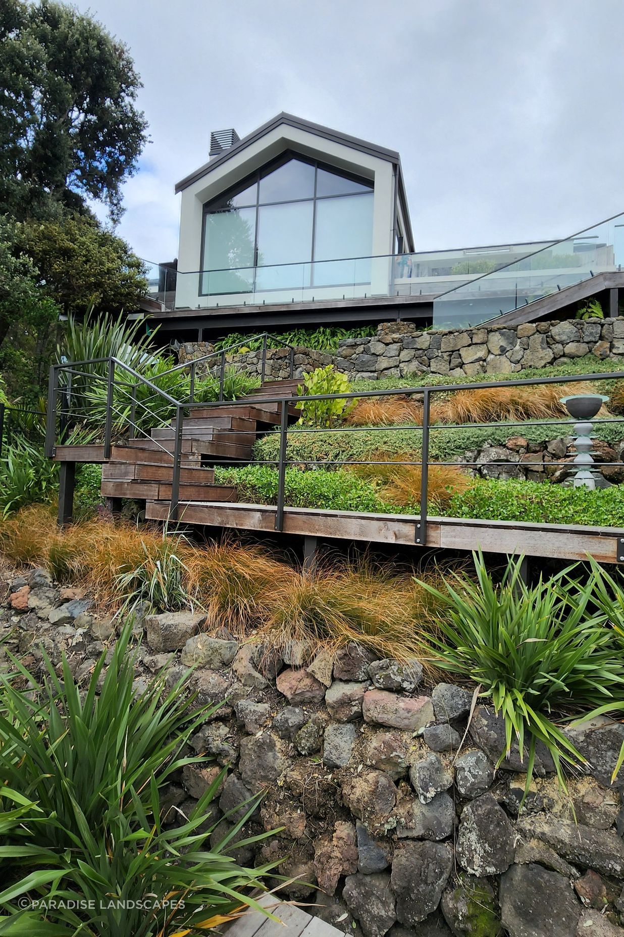 The steep site called for hardwood stairs to a deck surrounded by clusters of native shrubs.