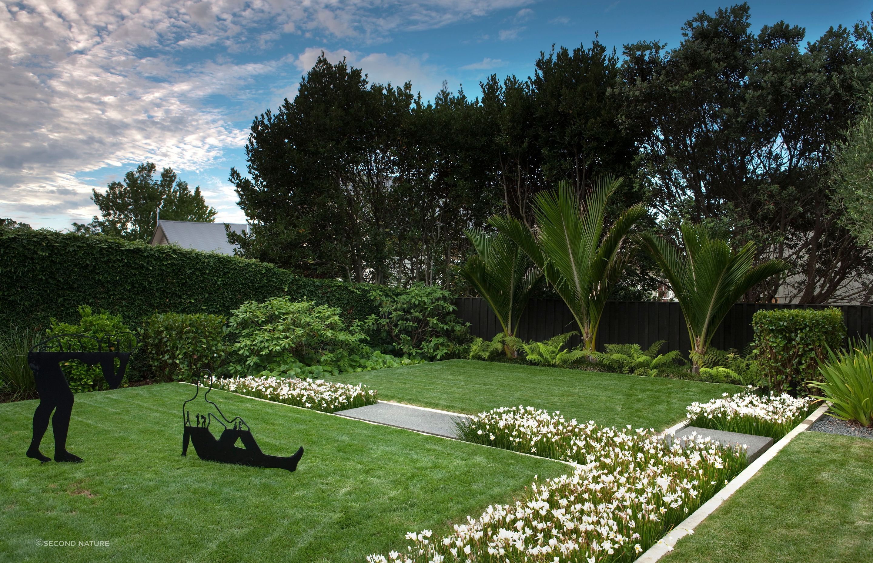 Second Nature uses lush flower beds to divide space in this suburban backyard.