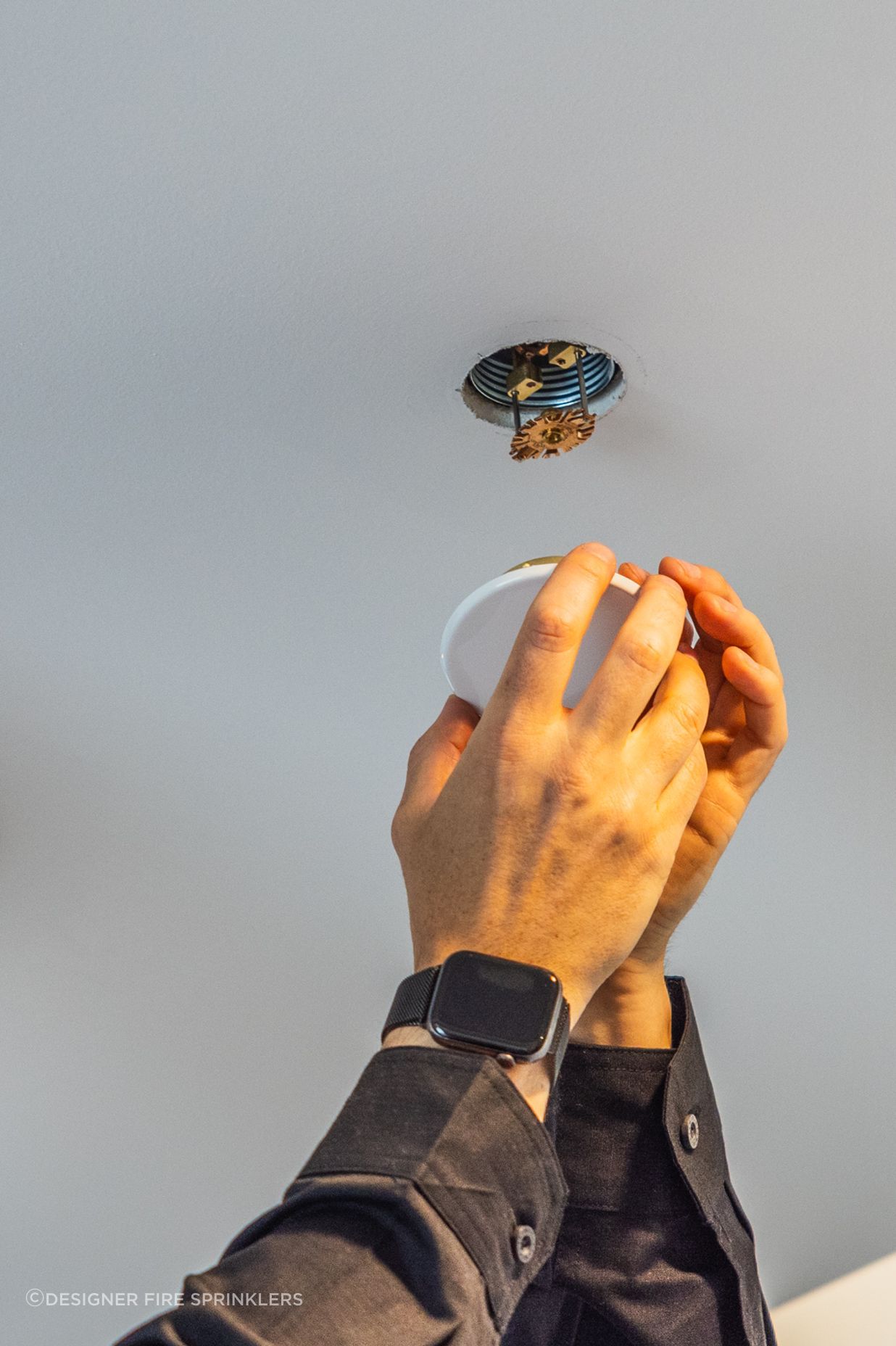 Designer Fire Sprinklers' co-founder Raphael Corbett installs a sprinkler unit.