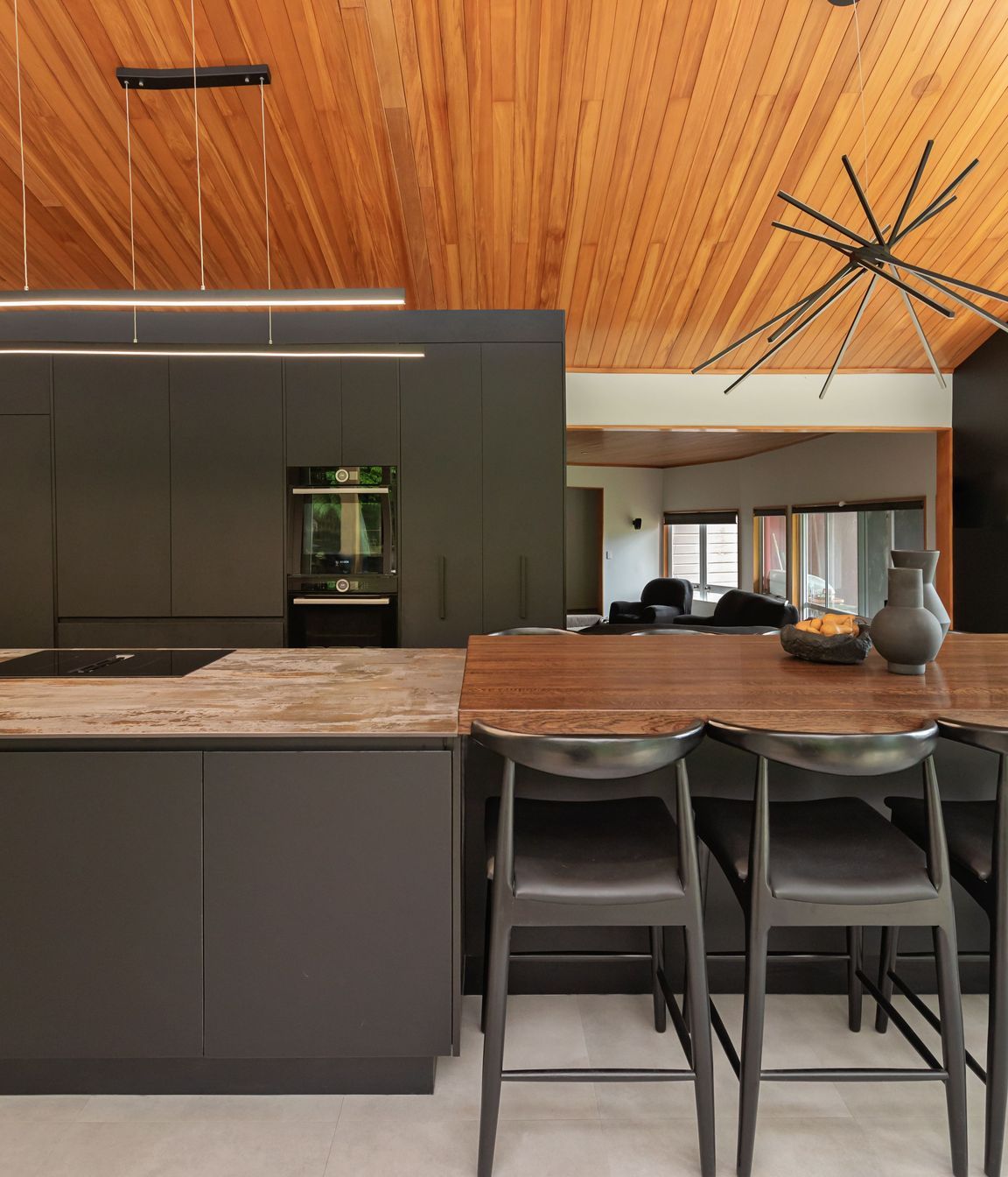 The variation in benchtop materials adds contrast and texture, visually dividing the dining area from the kitchen work zone.