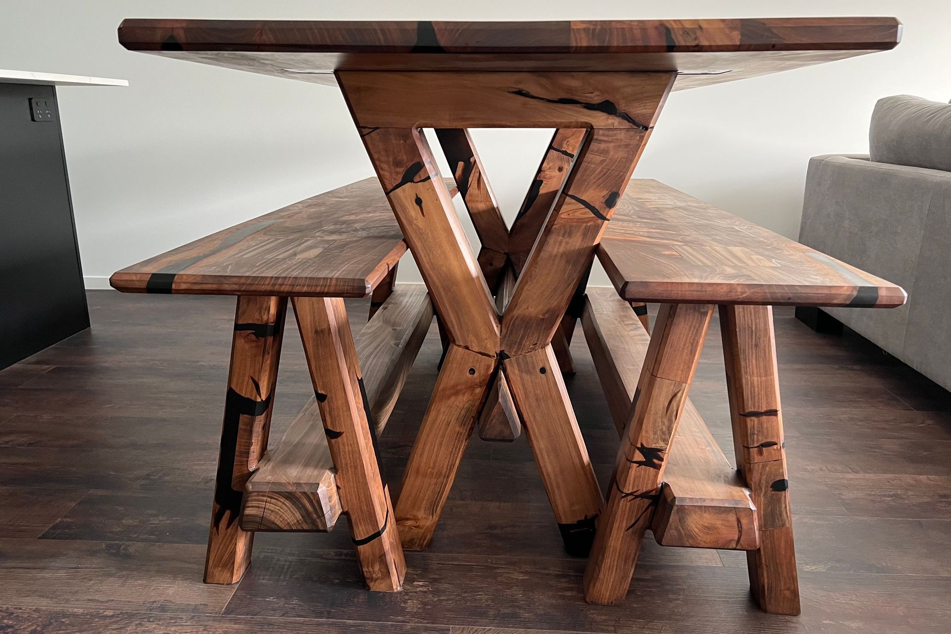Reclaimed macrocarpa timber from an old table has been used to create a new table and accompanying bench seats that encapsulate the unique character and history of the wood. Each imperfection in the timber has been transformed into a striking feature, accentuated by stunning black epoxy infills.