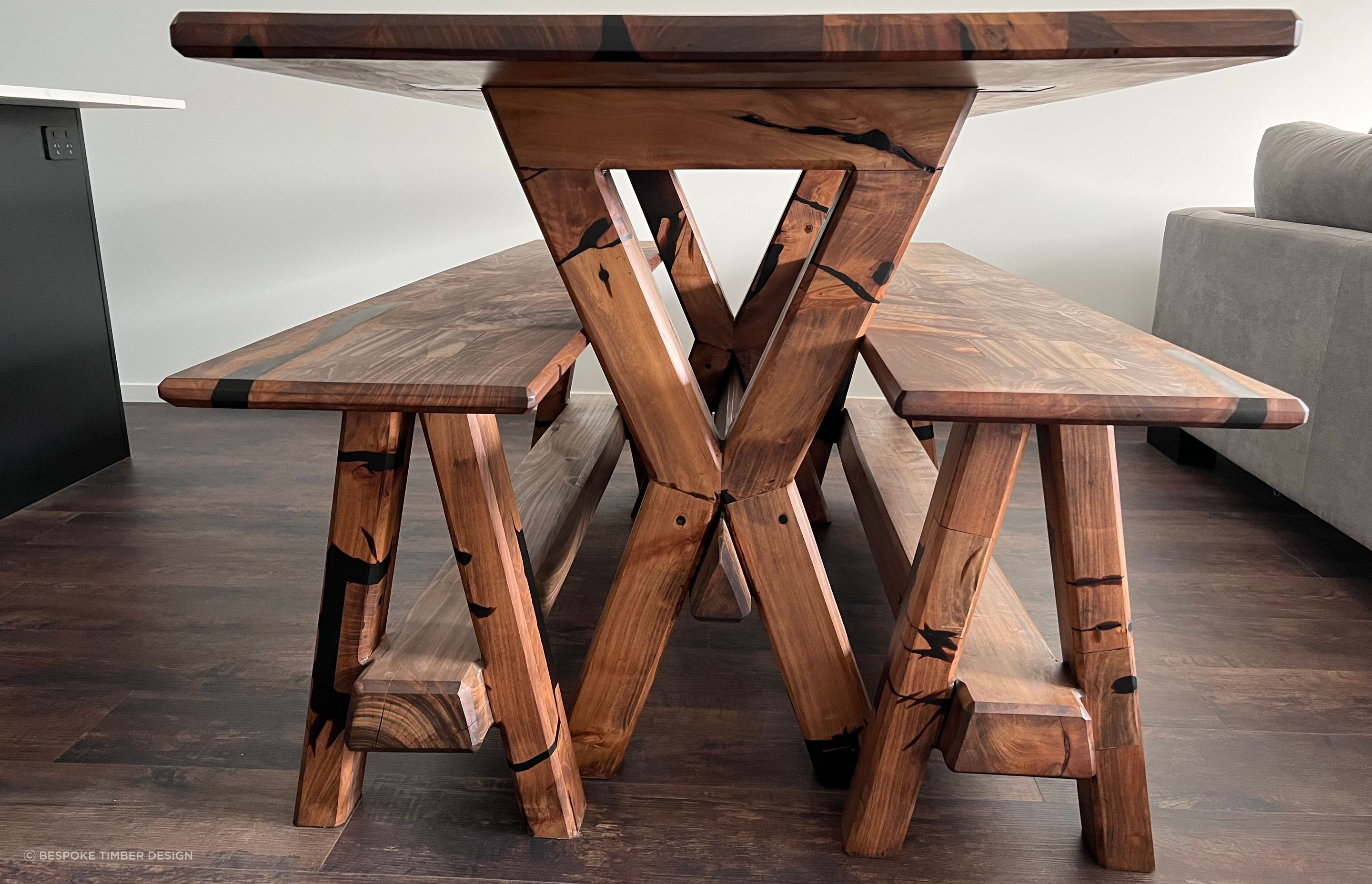 Reclaimed macrocarpa timber from an old table has been used to create a new table and accompanying bench seats that encapsulate the unique character and history of the wood. Each imperfection in the timber has been transformed into a striking feature, accentuated by stunning black epoxy infills.