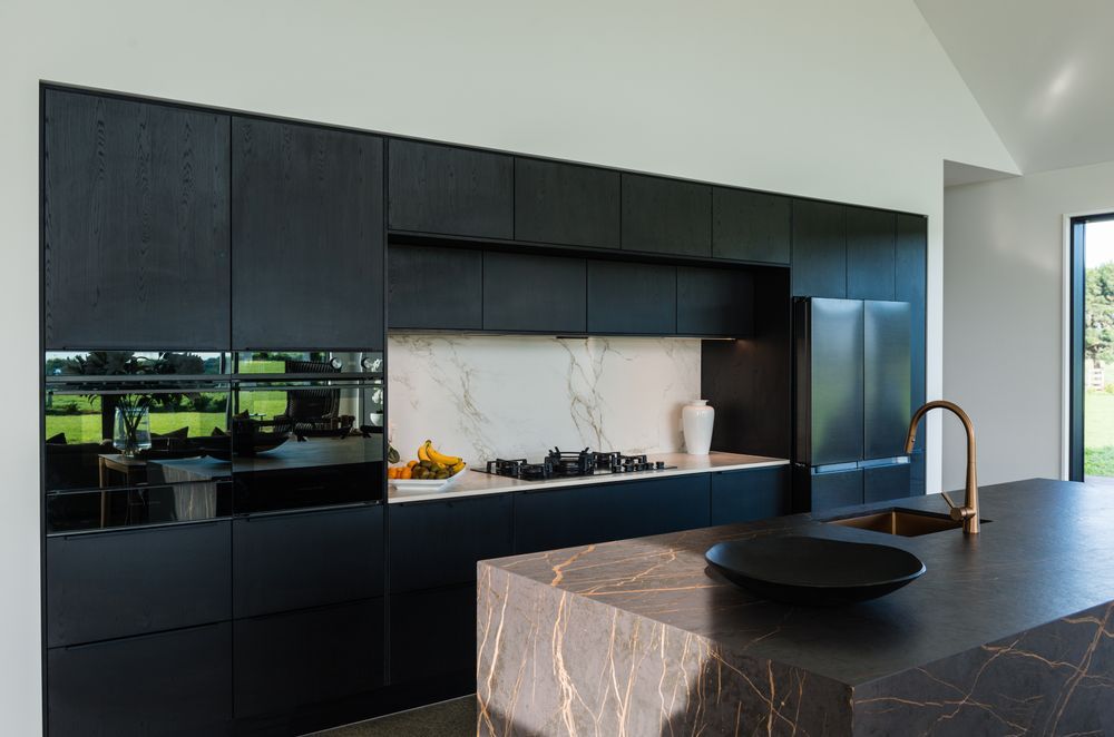 The lightness of the splashback rounds off the edges of the dark kitchen.