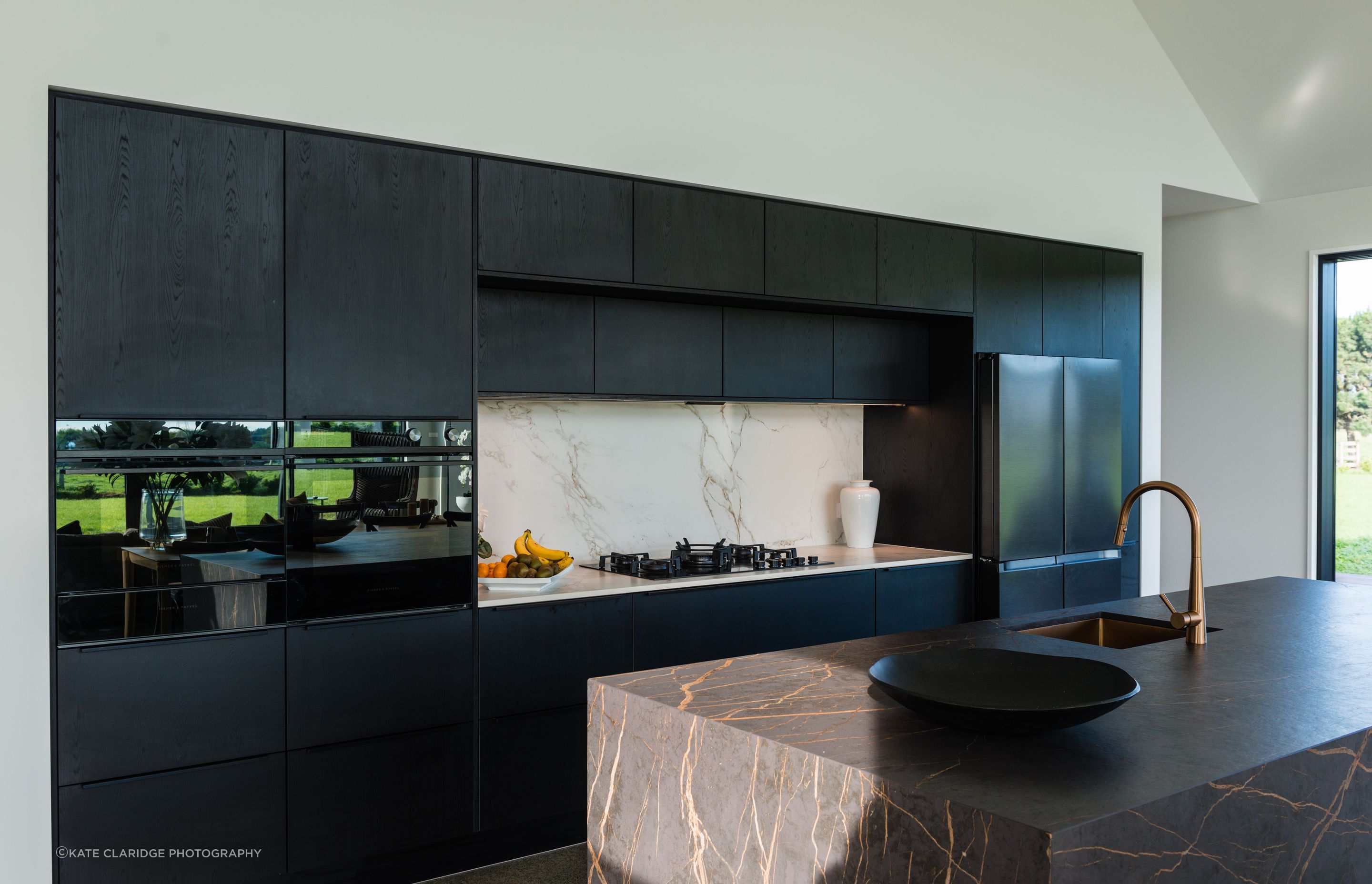 The lightness of the splashback rounds off the edges of the dark kitchen.