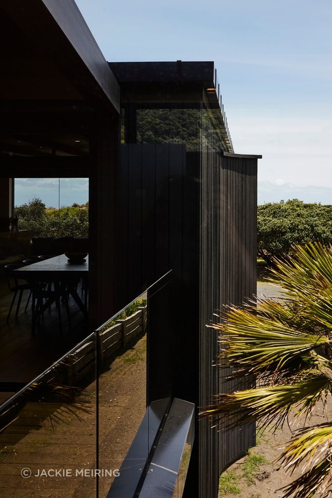 At Piha House, robust black-stained cedar and sheltered thresholds frame the quieter rituals of coastal living, bringing warmth, texture and domestic ease to an exposed west coast site.