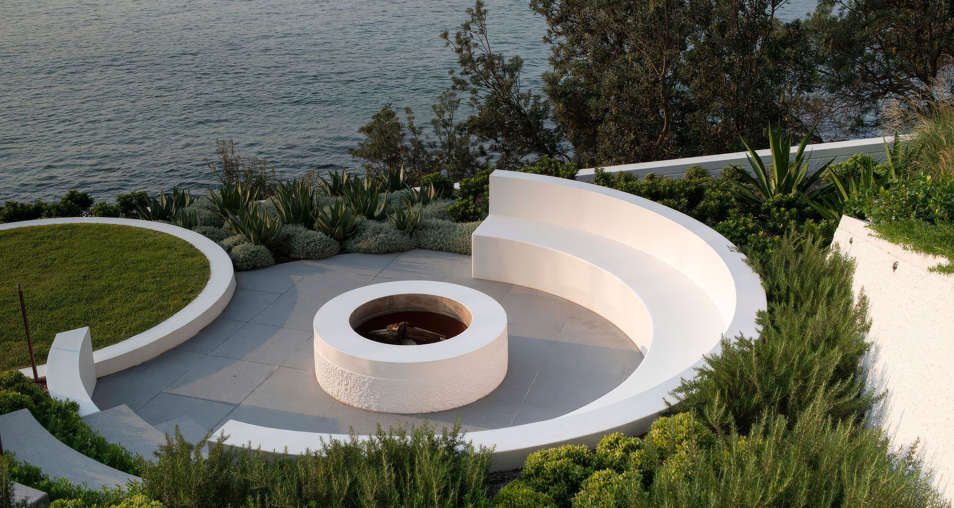At Cove House in Cronulla, curved garden beds, integrated seating and layered coastal planting extend the bold geometry of the original 1969 architecture into the landscape.