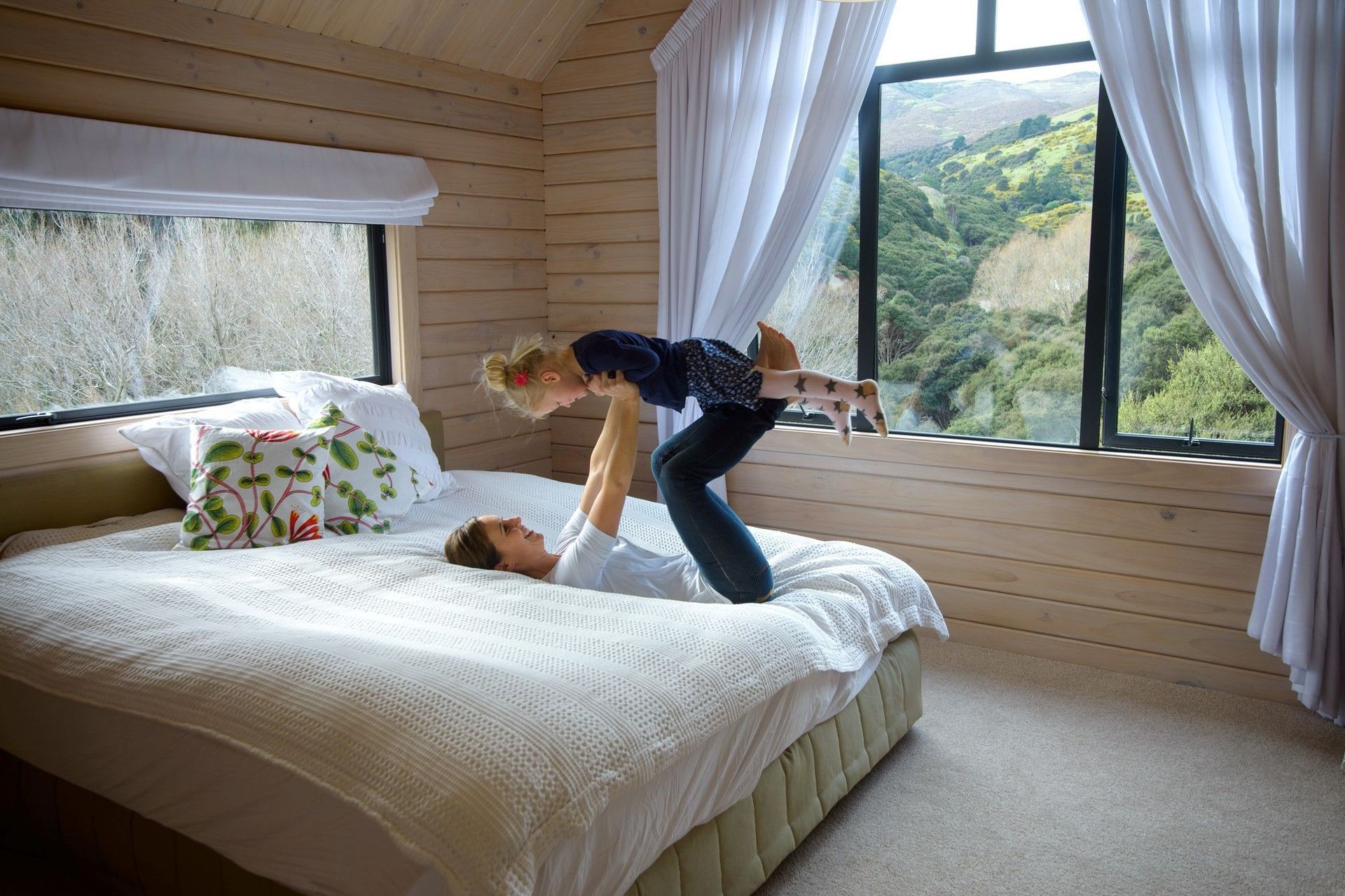 A neutral colour palette, as well as shades of green and blue, can create calming vibes in a bedroom, seen here in the stunning Split Level Timber Home on a Hill project in Tai Tapu