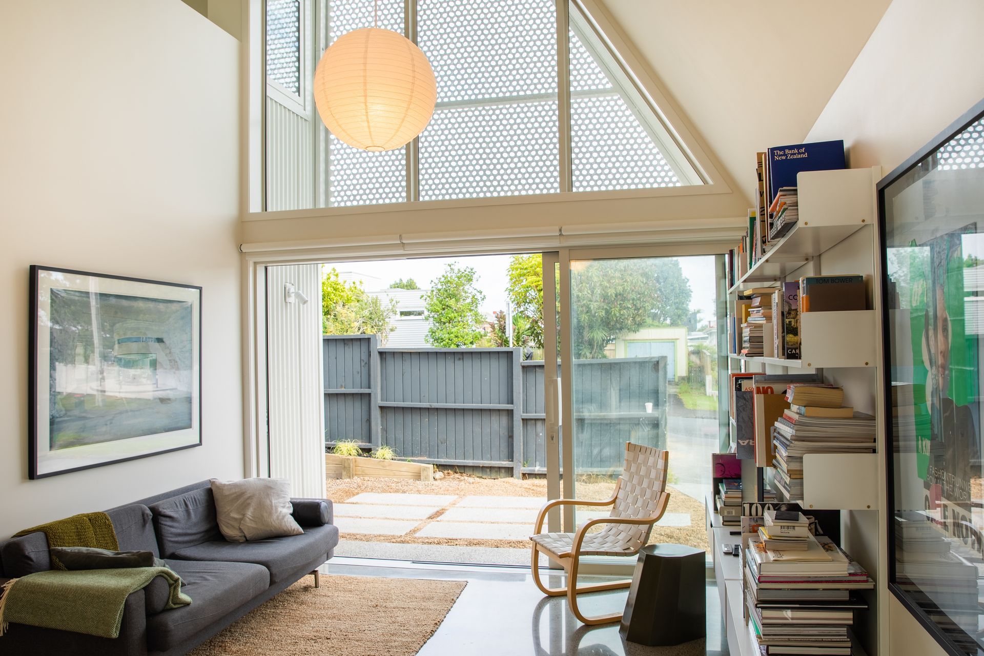 The perforated screen on the triangular window allows filtered light in and casts a pattern on the white walls.