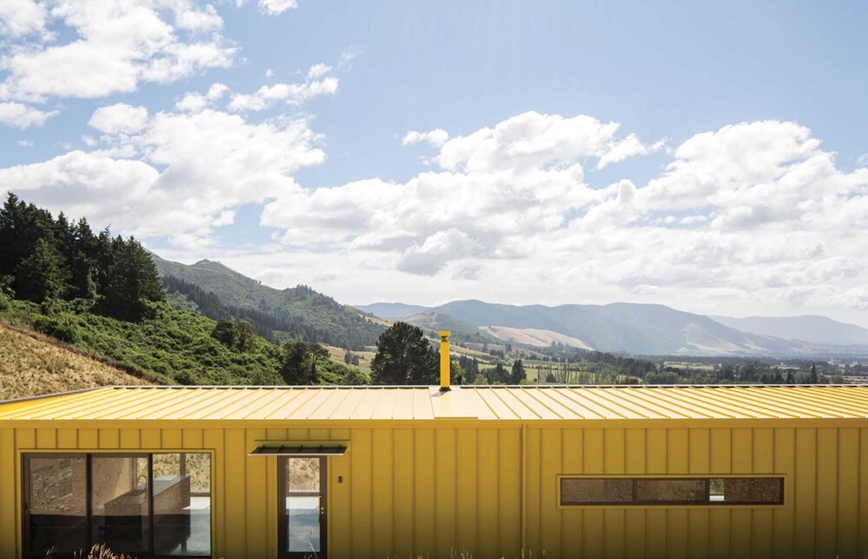 Exterior The exterior cladding on the walls and roof is an Espan tray roofing product in Kōwhai Glow.